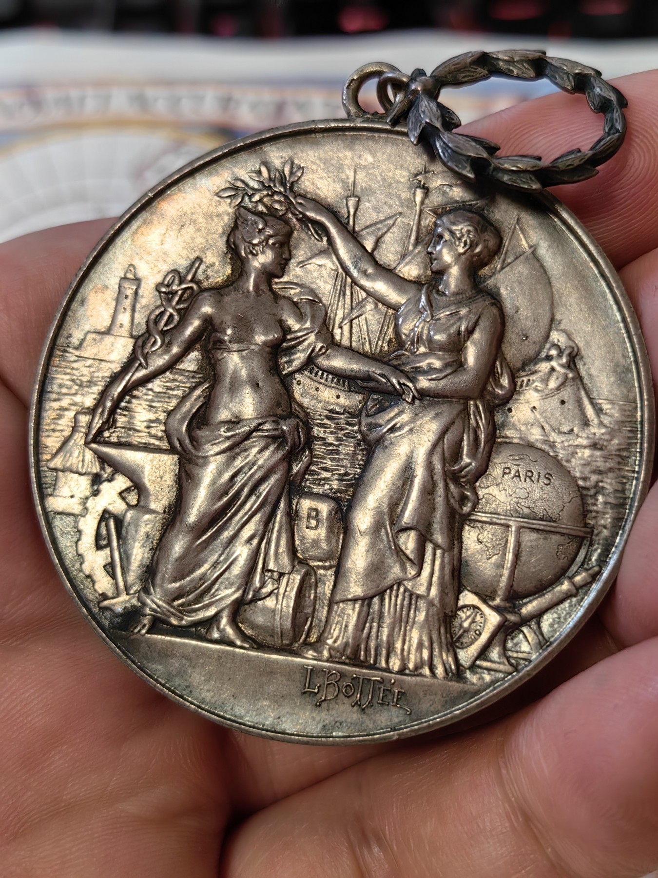 橡树集藏-006场 海纳百川 法国商业地理学会银奖章，1899 年。GEM 未流通。51毫米，58.92 克。作者：L.Botte。1899 年发行并赠送给卡米尔-莱昂-伊波利特·胡格南。正面：地理女神站在左侧，将月桂花环放在商业女神上，手持双杖；背景是商业和工业的标志，例如地球仪、敦、齿轮、铁砧、灯塔和船。完美出厂品相，高浮雕细节极佳，女神和天使柔美动人。