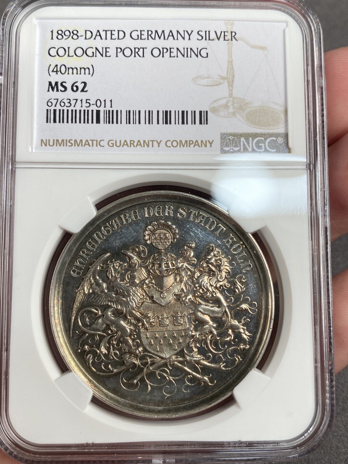 万国钱币拍卖第013期（视频直播专场） NGC MS62 1898年德国圣城科隆新港口开放典礼纪念大银章 欧洲彩，科隆城市纹章在币章中出现不多，此枚将圣城的狮鹫+雄狮盾徽完美的具象化了，非常难得和少见，40MM 22G