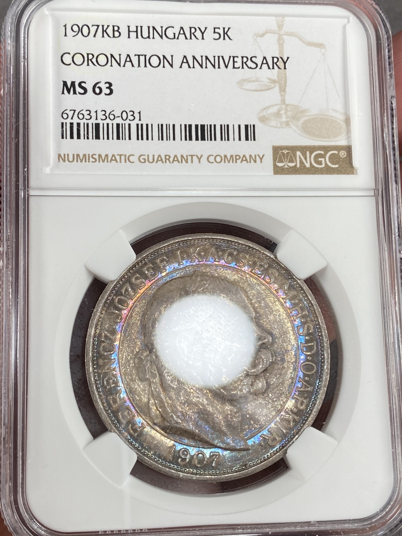 万国钱币拍卖第014期（奢华币宴第一季） NGC MS63 1907年奥地利原铸佛朗茨一世加冕纪念5克朗大银币 喷砂感强烈以及露出为数不多的币面来看 此枚有非常强烈的镜面表现 在幻彩包浆的遮盖下 也许是一枚误评的PROOFLIKE 