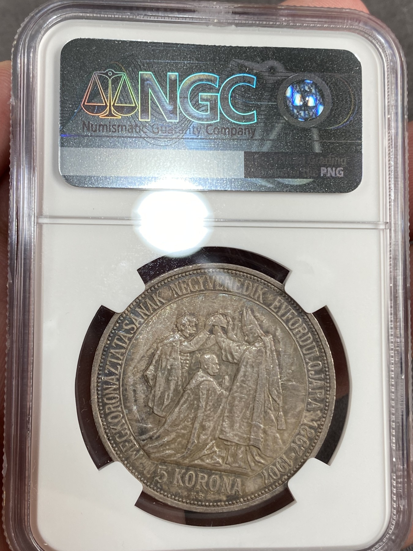 万国钱币拍卖第014期（奢华币宴第一季） NGC MS63 1907年奥地利原铸佛朗茨一世加冕纪念5克朗大银币 喷砂感强烈以及露出为数不多的币面来看 此枚有非常强烈的镜面表现 在幻彩包浆的遮盖下 也许是一枚误评的PROOFLIKE 