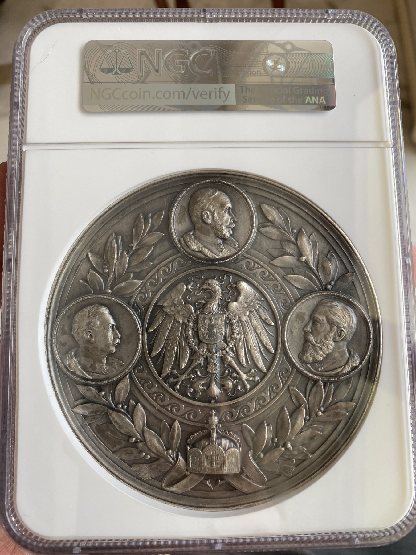 万国钱币拍卖第014期（奢华币宴第一季） NGC MS62 1898年德国帝国的脊梁俾斯麦逝世纪念大铜章 100MM 280G 正面的正面俾斯麦戎装像，上方为其年轻时期头像 左边为发表著名的铁血演讲 右边与威廉二世和解 下方为俾斯麦家族盾徽 背面普鲁士皇鹰加冕 三皇为其送终 此款章为俾斯麦中的精品 艺术感的设计均为当时的顶尖