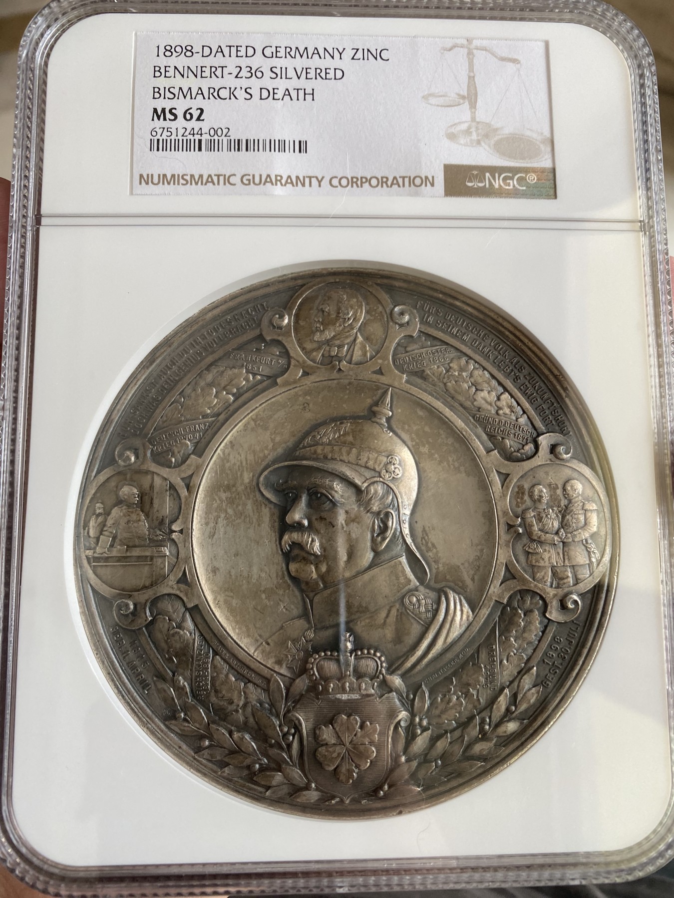 万国钱币拍卖第014期（奢华币宴第一季） NGC MS62 1898年德国帝国的脊梁俾斯麦逝世纪念大铜章 100MM 280G 正面的正面俾斯麦戎装像，上方为其年轻时期头像 左边为发表著名的铁血演讲 右边与威廉二世和解 下方为俾斯麦家族盾徽 背面普鲁士皇鹰加冕 三皇为其送终 此款章为俾斯麦中的精品 艺术感的设计均为当时的顶尖