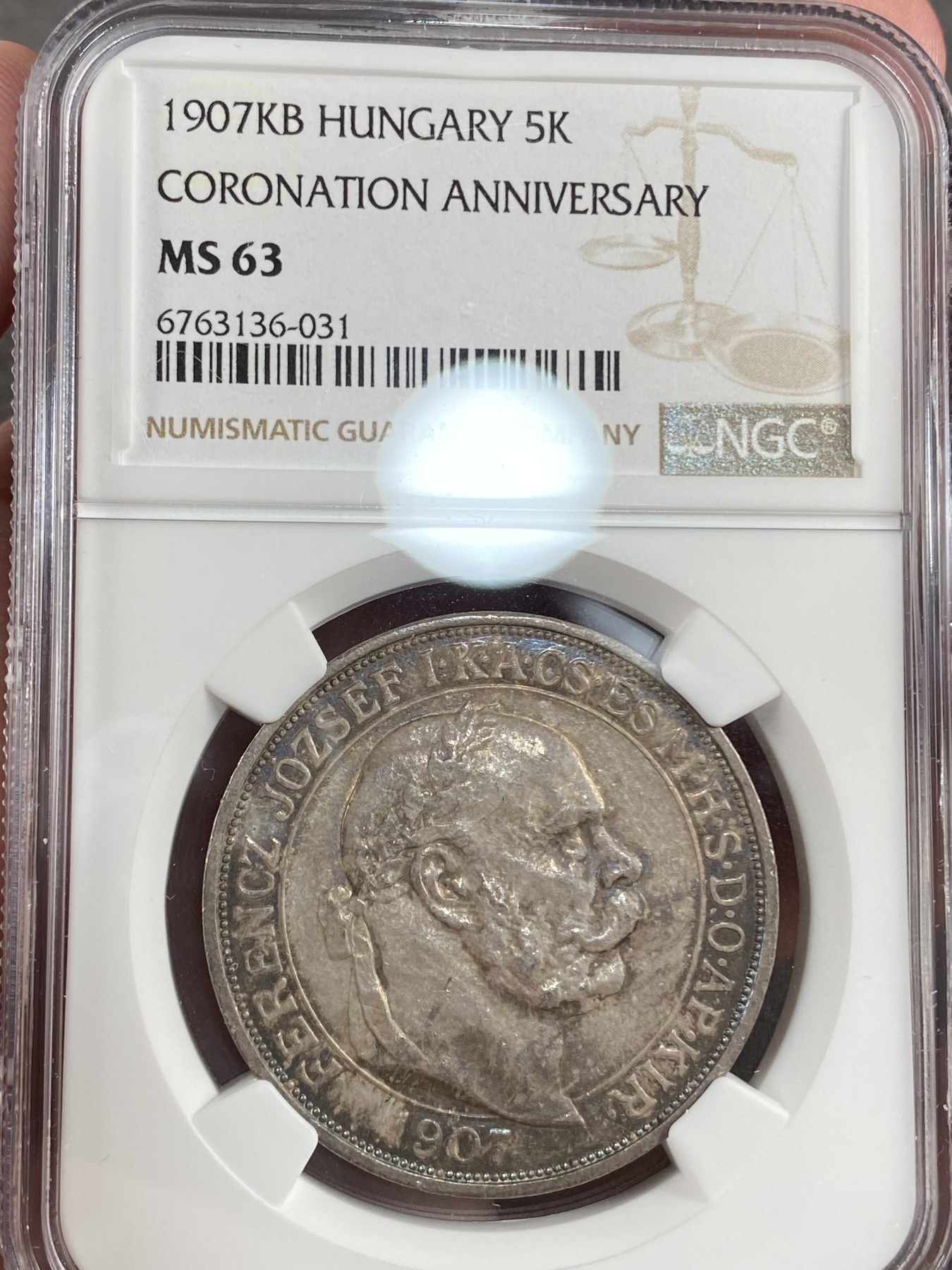万国钱币拍卖第014期（奢华币宴第一季） NGC MS63 1907年奥地利原铸佛朗茨一世加冕纪念5克朗大银币 喷砂感强烈以及露出为数不多的币面来看 此枚有非常强烈的镜面表现 在幻彩包浆的遮盖下 也许是一枚误评的PROOFLIKE 