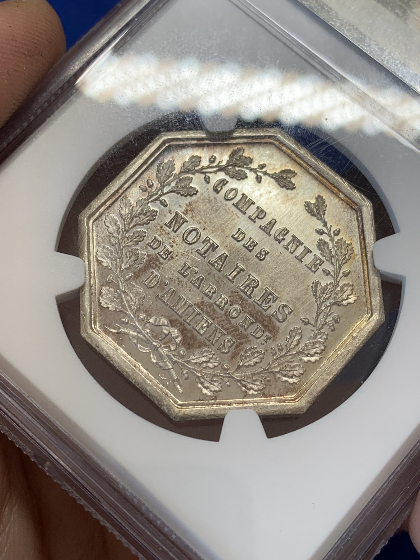 《竞宝斋》第207场-周日，周一 2场 (全场包邮) NGC-MS65 法国1854亚眠公证处天平八角银质八角代币，正面为典法后面的天平秤下方年份，背面为花枝环绕的铭文，顶级高分，丰饶角+ARGENT银标边铭，非常漂亮且少见的百年老银章原光五彩老包浆，状态极佳。