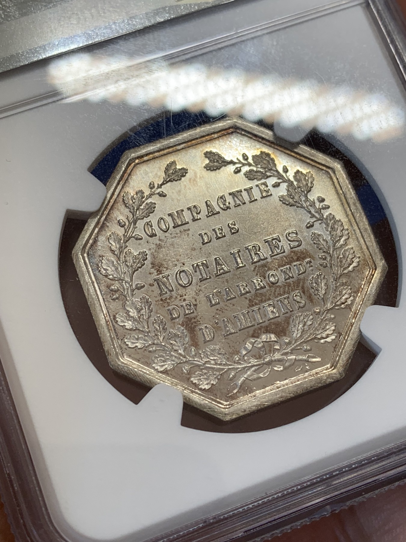 《竞宝斋》第207场-周日，周一 2场 (全场包邮) NGC-MS65 法国1854亚眠公证处天平八角银质八角代币，正面为典法后面的天平秤下方年份，背面为花枝环绕的铭文，顶级高分，丰饶角+ARGENT银标边铭，非常漂亮且少见的百年老银章原光五彩老包浆，状态极佳。