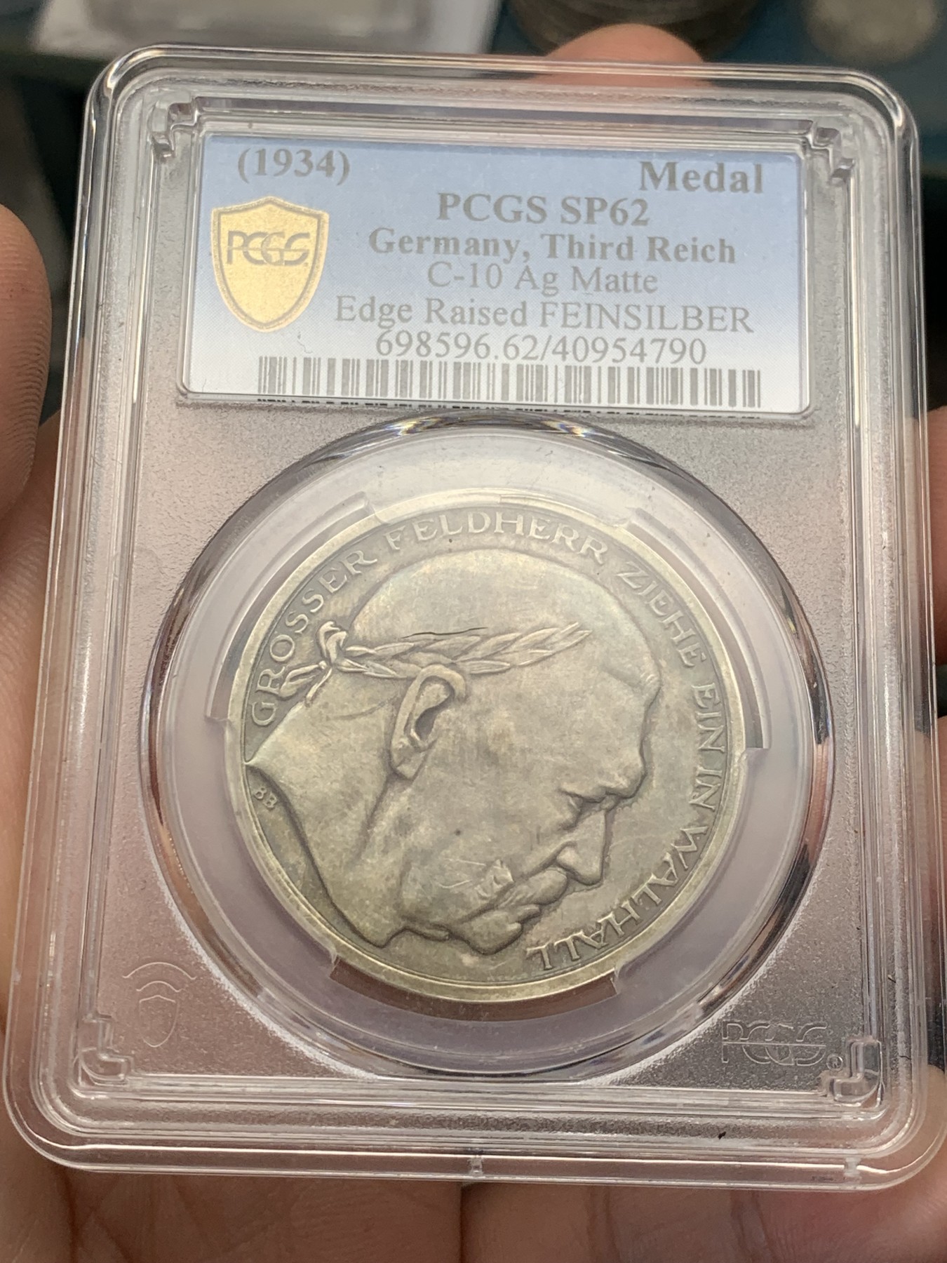 《竞宝斋》第207场-周日，周一 2场 (全场包邮) PCGS-SP62 德国1934年兴登堡交接纪念银章 炫彩包浆 带特殊标志 人物表面黑线为盒子小裂纹，多角度可见