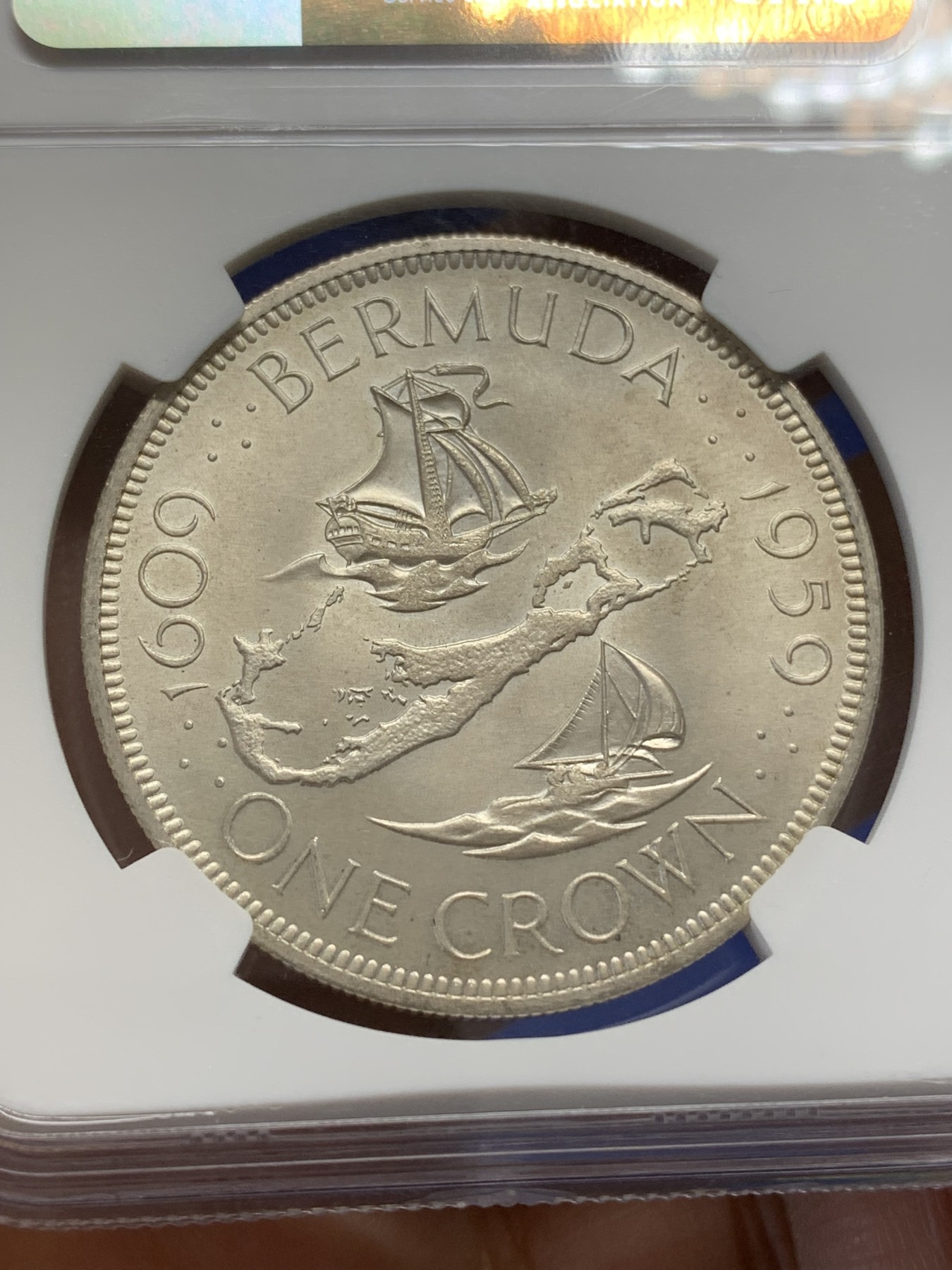 《竞宝斋》第218场-周日，周一 2场 (全场包邮) NGC-MS64 英属百慕大群岛1959年伊丽莎白二世1克朗银币，直径38mm，重28.28克，925银，发行量100010枚。自治的英国海外领地独立发行的首枚钱币。车轮转光，非常漂亮。