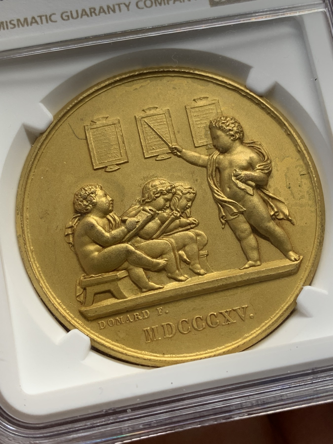 《竞宝斋》第223场-周日，周一 2场 (全场包邮) NGC-MS64 法国1907小天使教育学会铜质镀金奖章，四个小天使生动可爱，细节精美，惟妙惟肖。此版多见铜章，镀金版非常少见，镀层状态完美。