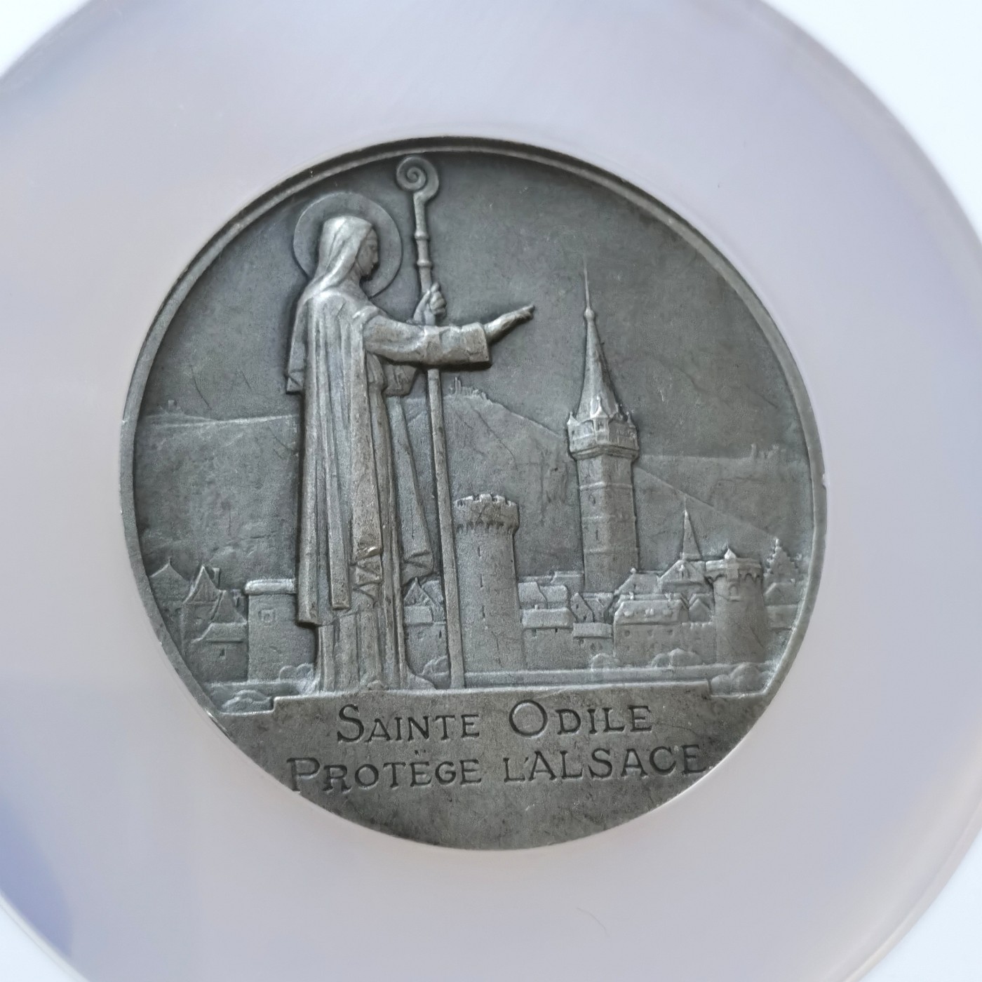 博洋堂世界钱币拍卖第056期（全场包邮） 法国1930年代银章阿尔萨斯的守护圣人圣奥蒂勒NGC MS63（雕刻家Morlon作品，58mm，110克，罕见银章品种！正面是圣奥蒂勒肖像，背面是在她守护之下的阿尔萨斯。圣奥蒂勒是法国阿尔萨斯的守护圣人。她生活在公元7世纪，是埃蒂松大公的女儿，由于出生时双目失明而被大公残忍遗弃。奥蒂勒被奶妈收养，后来在受洗日恢复视力并决定把一生奉献给主。历尽磨难之后，她父亲把城堡赠送给她，她在城堡里修建了自己的