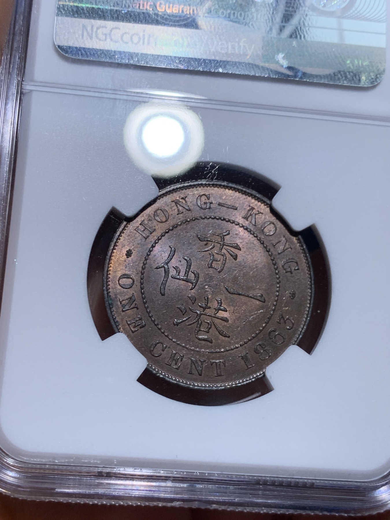 《竞宝斋》圣诞专辑  第一场  第227场 定制纪念章相赠 (全场顺丰包邮) NGC-MS63 香港1863年维多利亚女王香港一仙铜币。该品种流通币之首年，沿用了本土无神弗洛林的经典头像设计，背面是极具中国风味的文字排布，整币图案细腻文字工整，底板对光平滑，有一丝样币风范。以多点光源照射则光韵流畅盈满，辫子无常见弱打。巧克力色非常舒服，不输大多数64的状态，一步到位的东西。