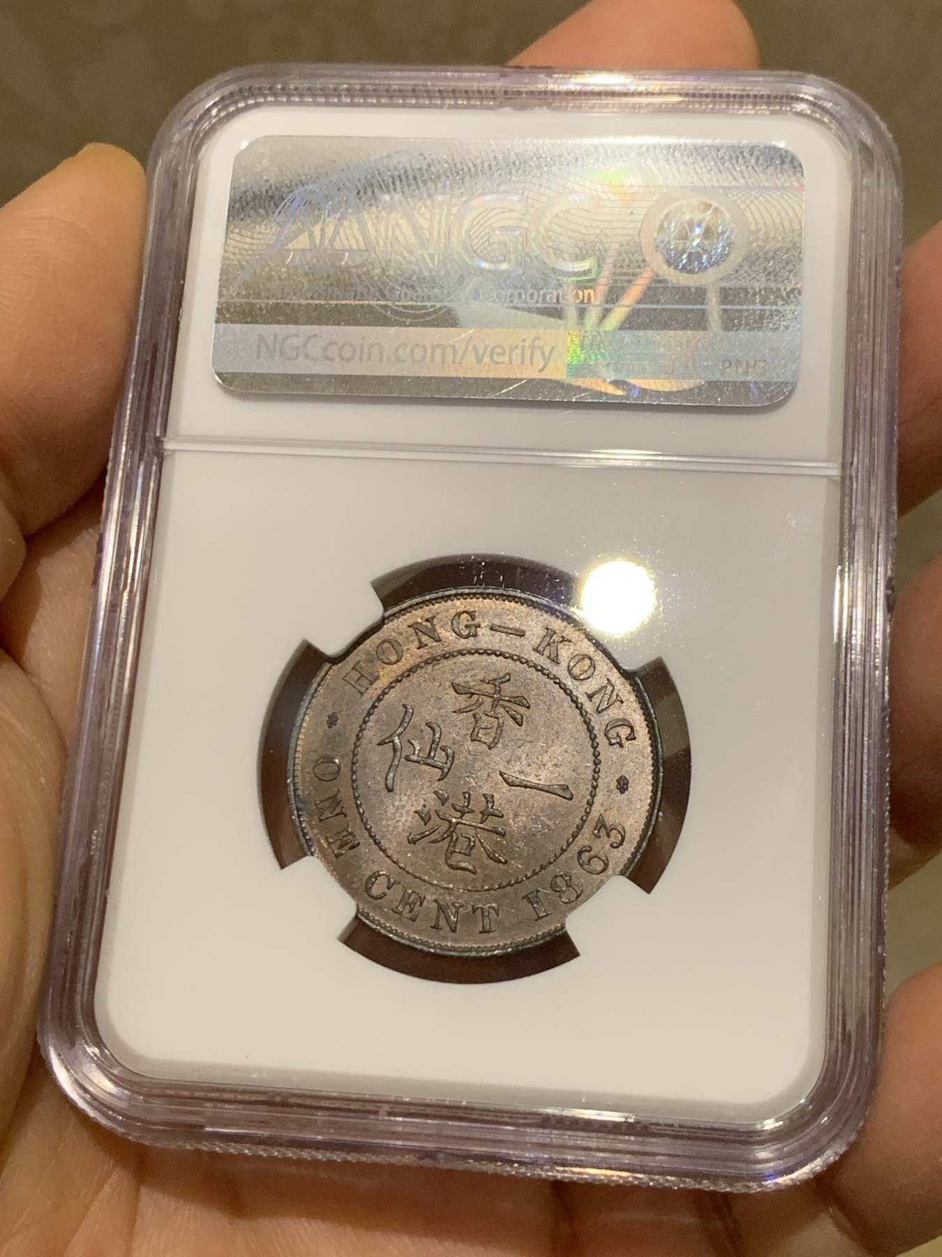 《竞宝斋》圣诞专辑  第一场  第227场 定制纪念章相赠 (全场顺丰包邮) NGC-MS63 香港1863年维多利亚女王香港一仙铜币。该品种流通币之首年，沿用了本土无神弗洛林的经典头像设计，背面是极具中国风味的文字排布，整币图案细腻文字工整，底板对光平滑，有一丝样币风范。以多点光源照射则光韵流畅盈满，辫子无常见弱打。巧克力色非常舒服，不输大多数64的状态，一步到位的东西。