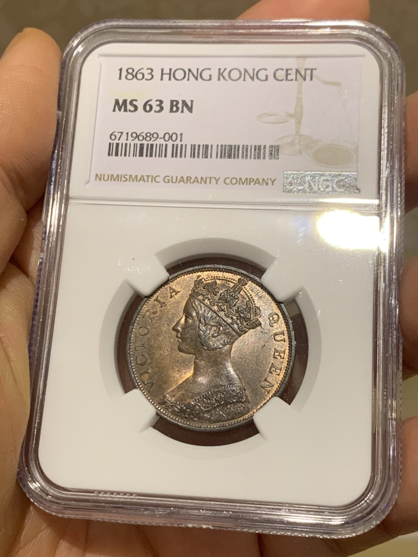 《竞宝斋》圣诞专辑  第一场  第227场 定制纪念章相赠 (全场顺丰包邮) NGC-MS63 香港1863年维多利亚女王香港一仙铜币。该品种流通币之首年，沿用了本土无神弗洛林的经典头像设计，背面是极具中国风味的文字排布，整币图案细腻文字工整，底板对光平滑，有一丝样币风范。以多点光源照射则光韵流畅盈满，辫子无常见弱打。巧克力色非常舒服，不输大多数64的状态，一步到位的东西。