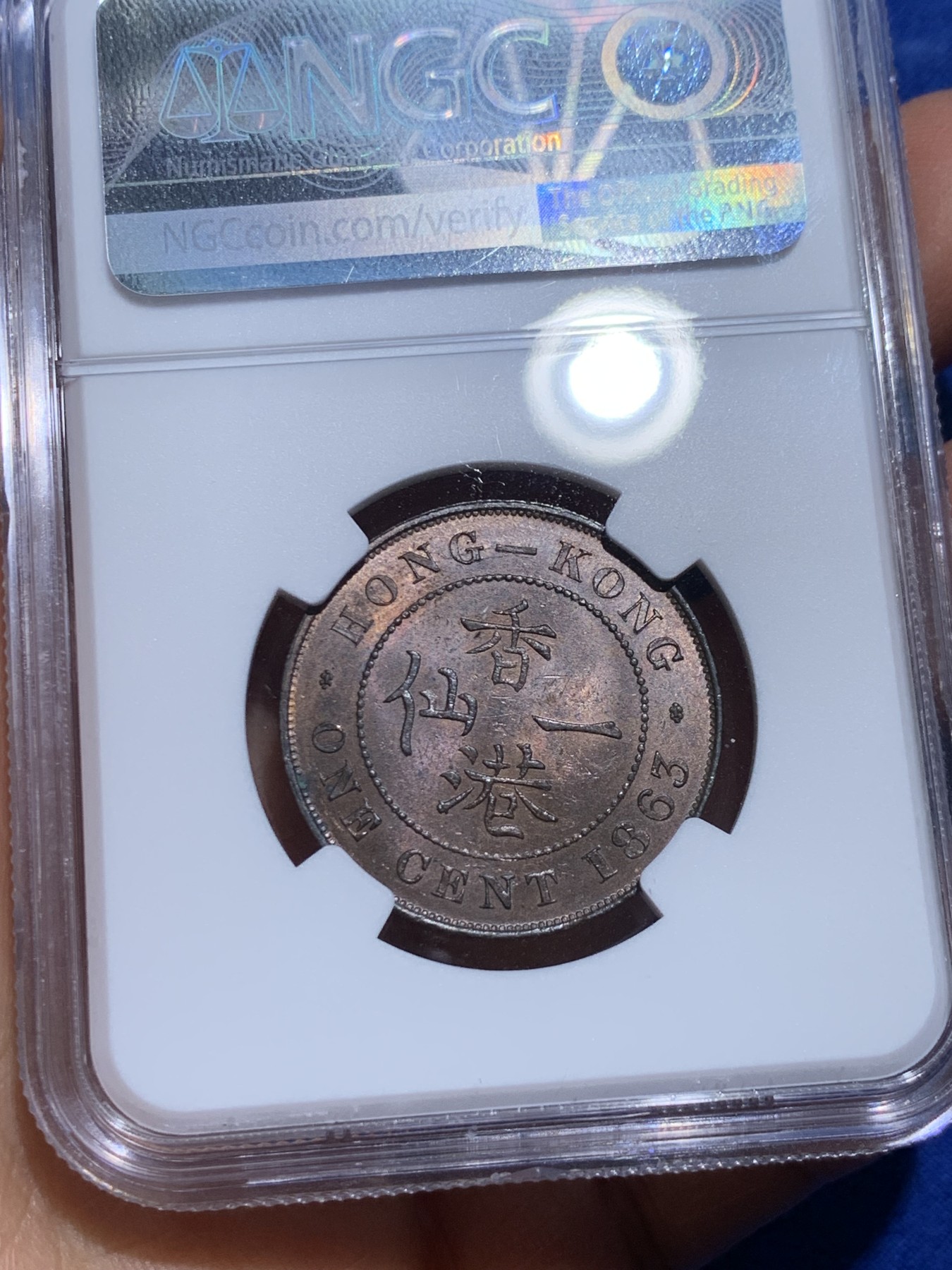 《竞宝斋》圣诞专辑  第一场  第227场 定制纪念章相赠 (全场顺丰包邮) NGC-MS63 香港1863年维多利亚女王香港一仙铜币。该品种流通币之首年，沿用了本土无神弗洛林的经典头像设计，背面是极具中国风味的文字排布，整币图案细腻文字工整，底板对光平滑，有一丝样币风范。以多点光源照射则光韵流畅盈满，辫子无常见弱打。巧克力色非常舒服，不输大多数64的状态，一步到位的东西。