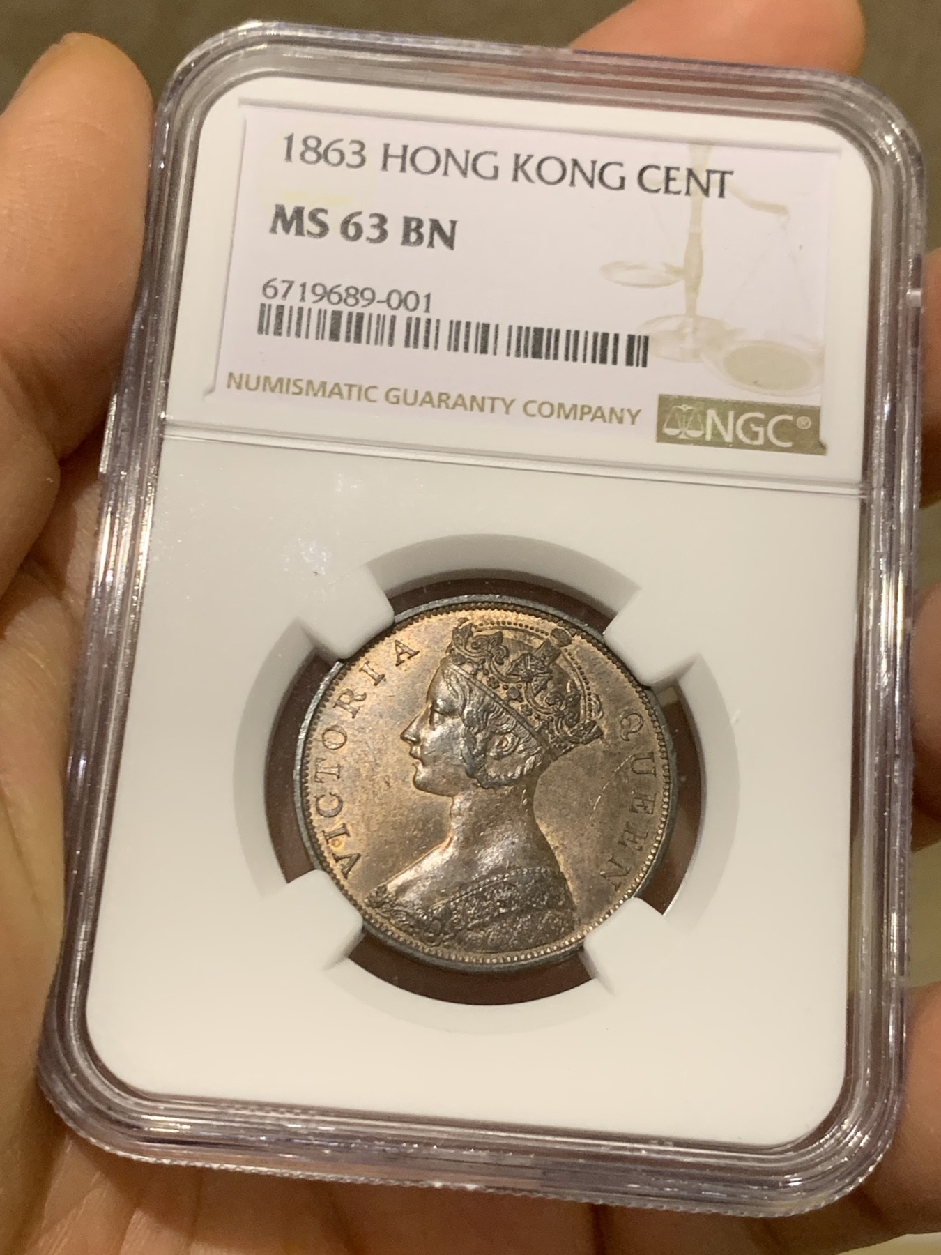 《竞宝斋》圣诞专辑  第一场  第227场 定制纪念章相赠 (全场顺丰包邮) NGC-MS63 香港1863年维多利亚女王香港一仙铜币。该品种流通币之首年，沿用了本土无神弗洛林的经典头像设计，背面是极具中国风味的文字排布，整币图案细腻文字工整，底板对光平滑，有一丝样币风范。以多点光源照射则光韵流畅盈满，辫子无常见弱打。巧克力色非常舒服，不输大多数64的状态，一步到位的东西。