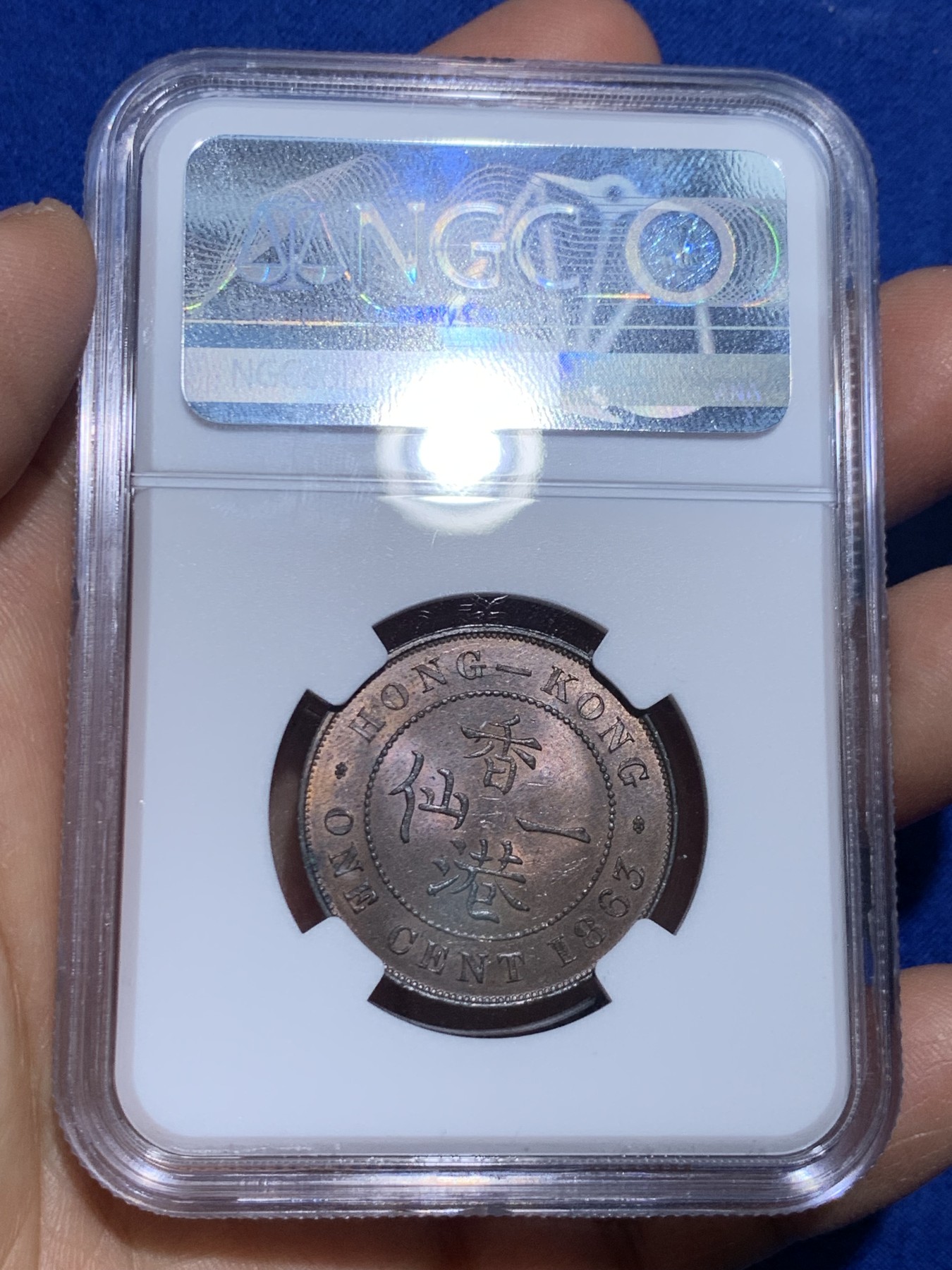 《竞宝斋》圣诞专辑  第一场  第227场 定制纪念章相赠 (全场顺丰包邮) NGC-MS63 香港1863年维多利亚女王香港一仙铜币。该品种流通币之首年，沿用了本土无神弗洛林的经典头像设计，背面是极具中国风味的文字排布，整币图案细腻文字工整，底板对光平滑，有一丝样币风范。以多点光源照射则光韵流畅盈满，辫子无常见弱打。巧克力色非常舒服，不输大多数64的状态，一步到位的东西。