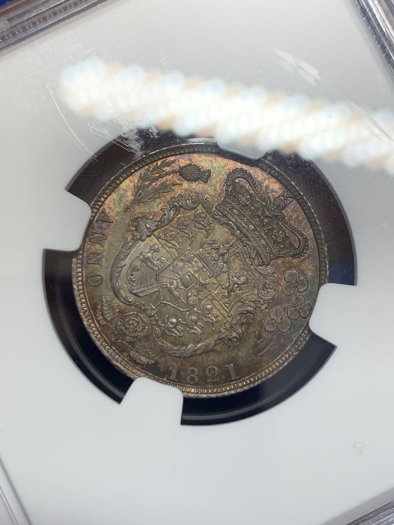 《竞宝斋》圣诞专辑  第二场  第228场 定制纪念章相赠 (全场顺丰包邮) NGC-MS66 英国1821年乔治四世1先令银币。币面环绕暖色系包浆，橘黄，红酒色，梅红，紫罗兰循序渐进。双面经典，正面头像来自皮斯特鲁奇；背面三花图案来自简·帕皮提斯特·梅林，签名隐藏在内齿。三叶草上暗记wwp为mint master的简拼。美国知名币商66+售价1850美金。