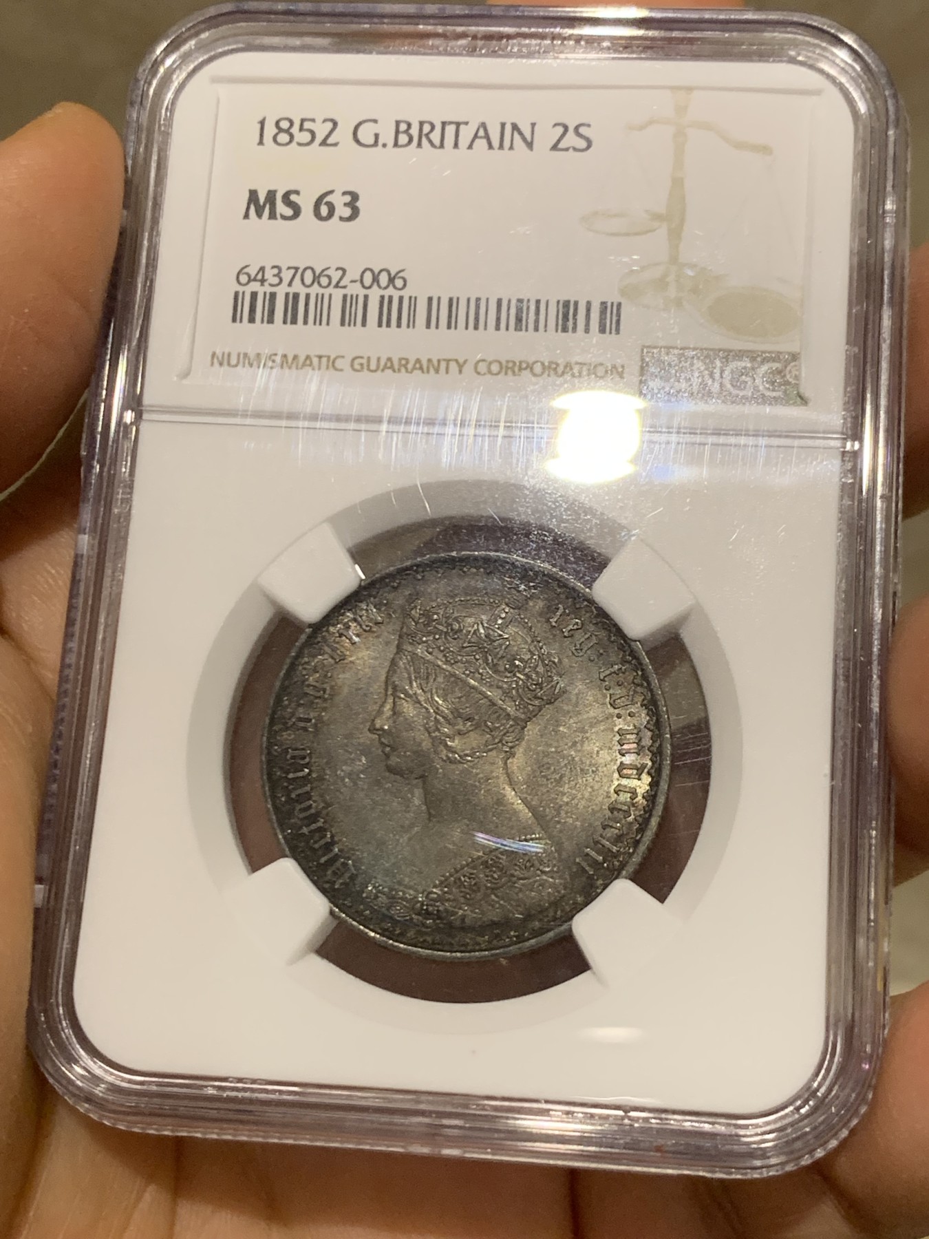 《竞宝斋》圣诞专辑  第二场  第228场 定制纪念章相赠 (全场顺丰包邮) NGC-MS63 英国1852年维多利亚女王哥特福林银币。正面包浆沉稳古气，但又能透出隐约的酒红光芒，背面是极其漂亮的五彩彩虹色过渡自然。这枚是整个系列的第一年，第一版女王面部线条和蔼柔美，值得入手。