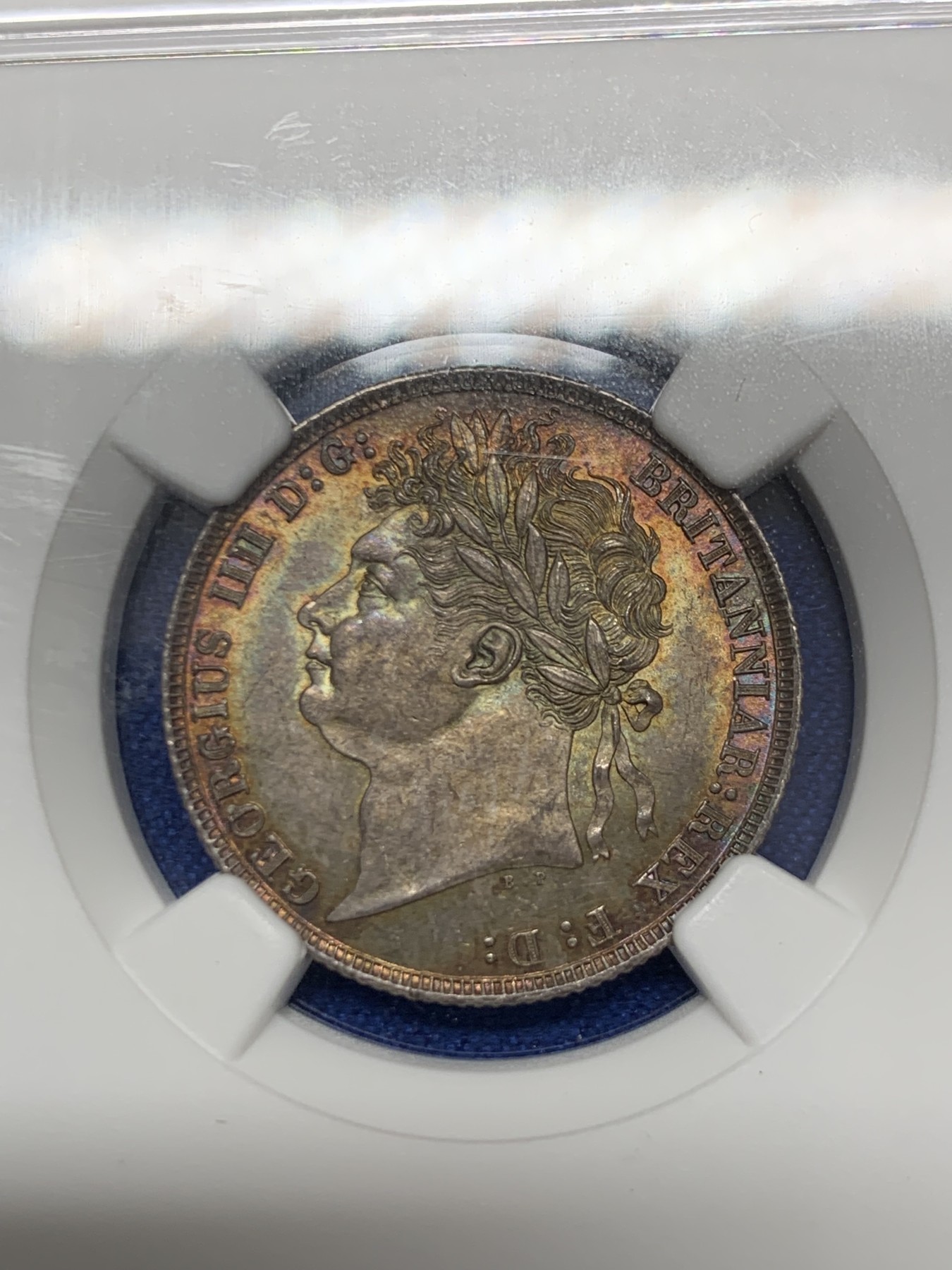 《竞宝斋》圣诞专辑  第二场  第228场 定制纪念章相赠 (全场顺丰包邮) NGC-MS66 英国1821年乔治四世1先令银币。币面环绕暖色系包浆，橘黄，红酒色，梅红，紫罗兰循序渐进。双面经典，正面头像来自皮斯特鲁奇；背面三花图案来自简·帕皮提斯特·梅林，签名隐藏在内齿。三叶草上暗记wwp为mint master的简拼。美国知名币商66+售价1850美金。