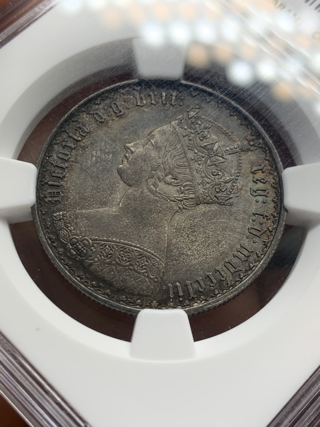 《竞宝斋》圣诞专辑  第二场  第228场 定制纪念章相赠 (全场顺丰包邮) NGC-MS63 英国1852年维多利亚女王哥特福林银币。正面包浆沉稳古气，但又能透出隐约的酒红光芒，背面是极其漂亮的五彩彩虹色过渡自然。这枚是整个系列的第一年，第一版女王面部线条和蔼柔美，值得入手。
