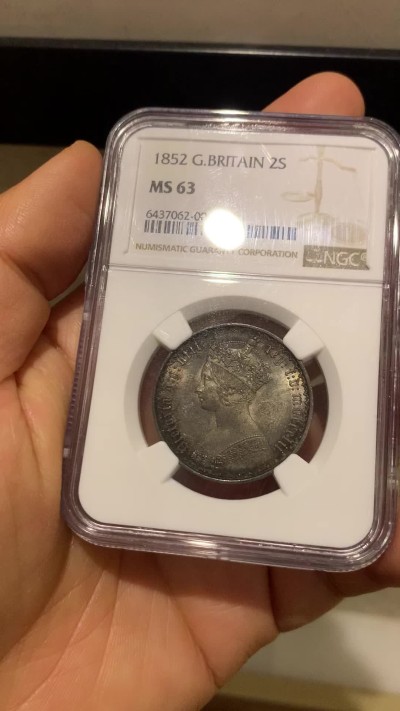 《竞宝斋》圣诞专辑  第二场  第228场 定制纪念章相赠 (全场顺丰包邮) NGC-MS63 英国1852年维多利亚女王哥特福林银币。正面包浆沉稳古气，但又能透出隐约的酒红光芒，背面是极其漂亮的五彩彩虹色过渡自然。这枚是整个系列的第一年，第一版女王面部线条和蔼柔美，值得入手。