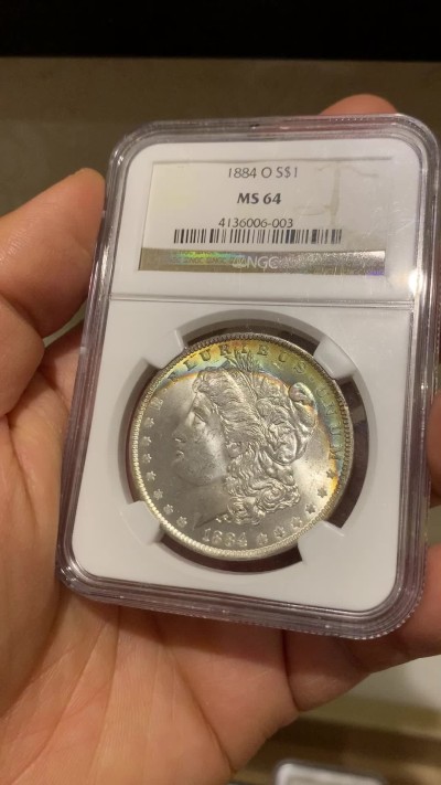 《竞宝斋》圣诞专辑  第二场  第228场 定制纪念章相赠 (全场顺丰包邮) NGC老盒评级MS64分。1884年O版摩根银元，月牙彩，彩虹包浆，好看包浆的摩根相比普通摩根海外溢价很高。今年汇率上涨，摩根是抗通胀好品种，64好彩勿错过。