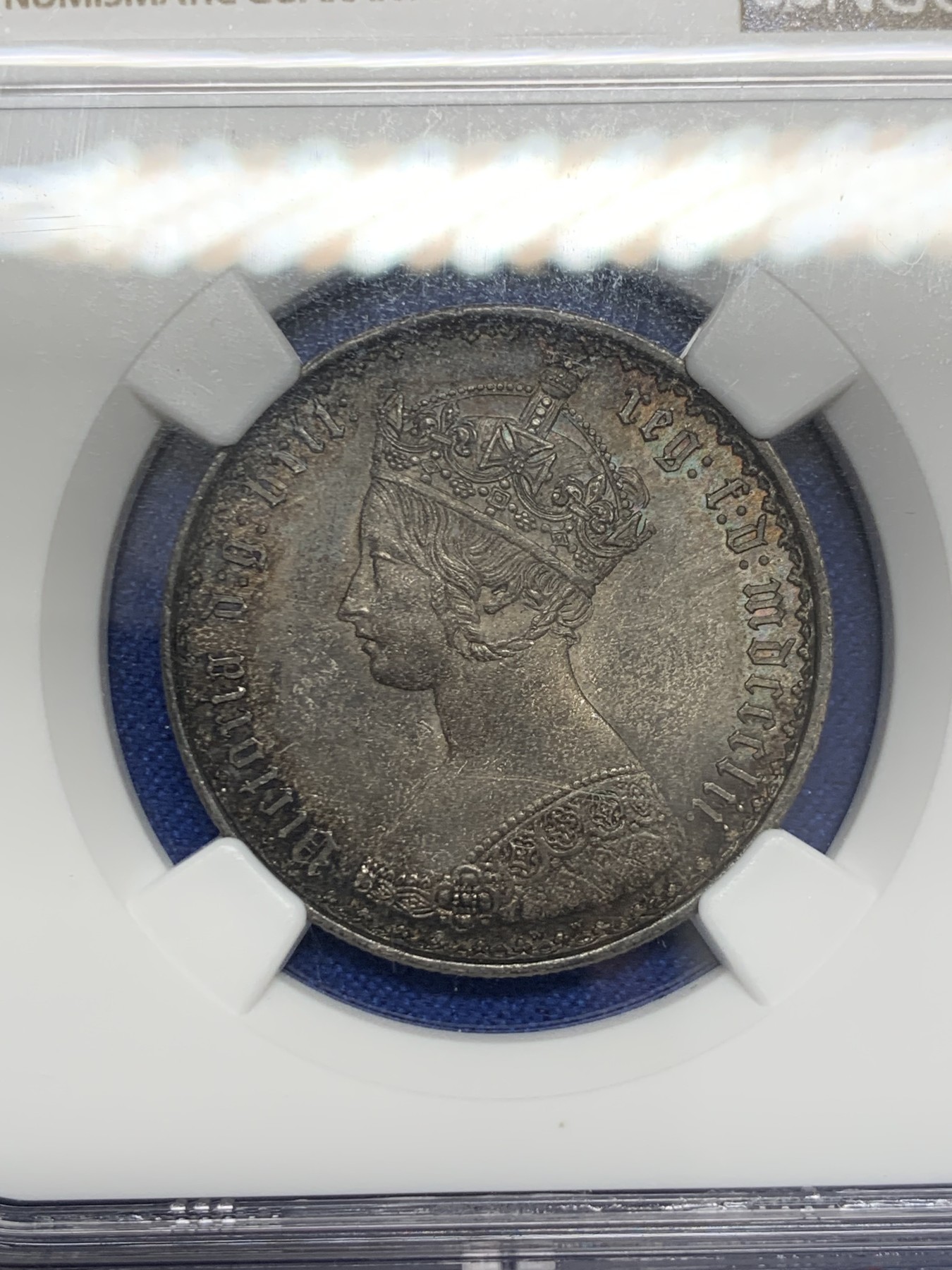 《竞宝斋》圣诞专辑  第二场  第228场 定制纪念章相赠 (全场顺丰包邮) NGC-MS63 英国1852年维多利亚女王哥特福林银币。正面包浆沉稳古气，但又能透出隐约的酒红光芒，背面是极其漂亮的五彩彩虹色过渡自然。这枚是整个系列的第一年，第一版女王面部线条和蔼柔美，值得入手。