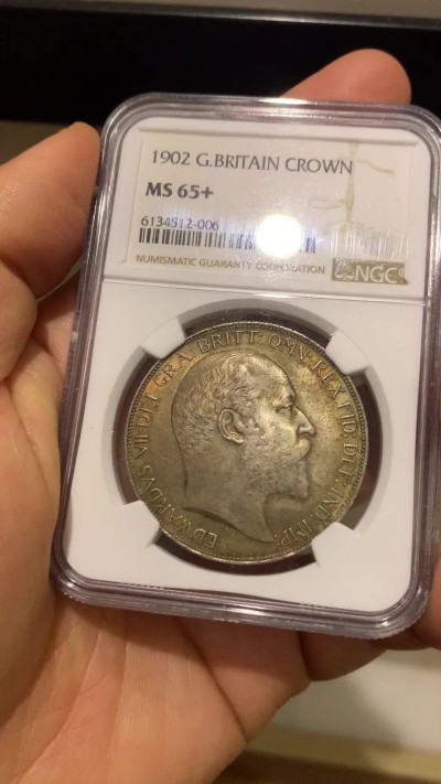 《竞宝斋》圣诞专辑  第二场  第228场 定制纪念章相赠 (全场顺丰包邮) NGC-MS65+ 英国1902年爱德华七世 克朗。双面都带有着原生的赤红的包浆。调查np数据库不难发现，该品种精制的高分数量接近普制的3倍，且该品种常见的苍蝇脚在此币上完全不可见，可惜打制稍弱让该币无法获评66分，但是其如水面波纹流转的转光依然在该品种内难见敌手。一年内的成交价：HA的pf-66/7800美元，苏尔曼pf-66落槌5000欧，英拍pf-65+落槌2800镑。普制高分已有数年未有在