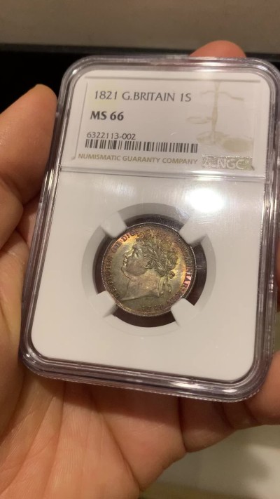 《竞宝斋》圣诞专辑  第二场  第228场 定制纪念章相赠 (全场顺丰包邮) NGC-MS66 英国1821年乔治四世1先令银币。币面环绕暖色系包浆，橘黄，红酒色，梅红，紫罗兰循序渐进。双面经典，正面头像来自皮斯特鲁奇；背面三花图案来自简·帕皮提斯特·梅林，签名隐藏在内齿。三叶草上暗记wwp为mint master的简拼。美国知名币商66+售价1850美金。