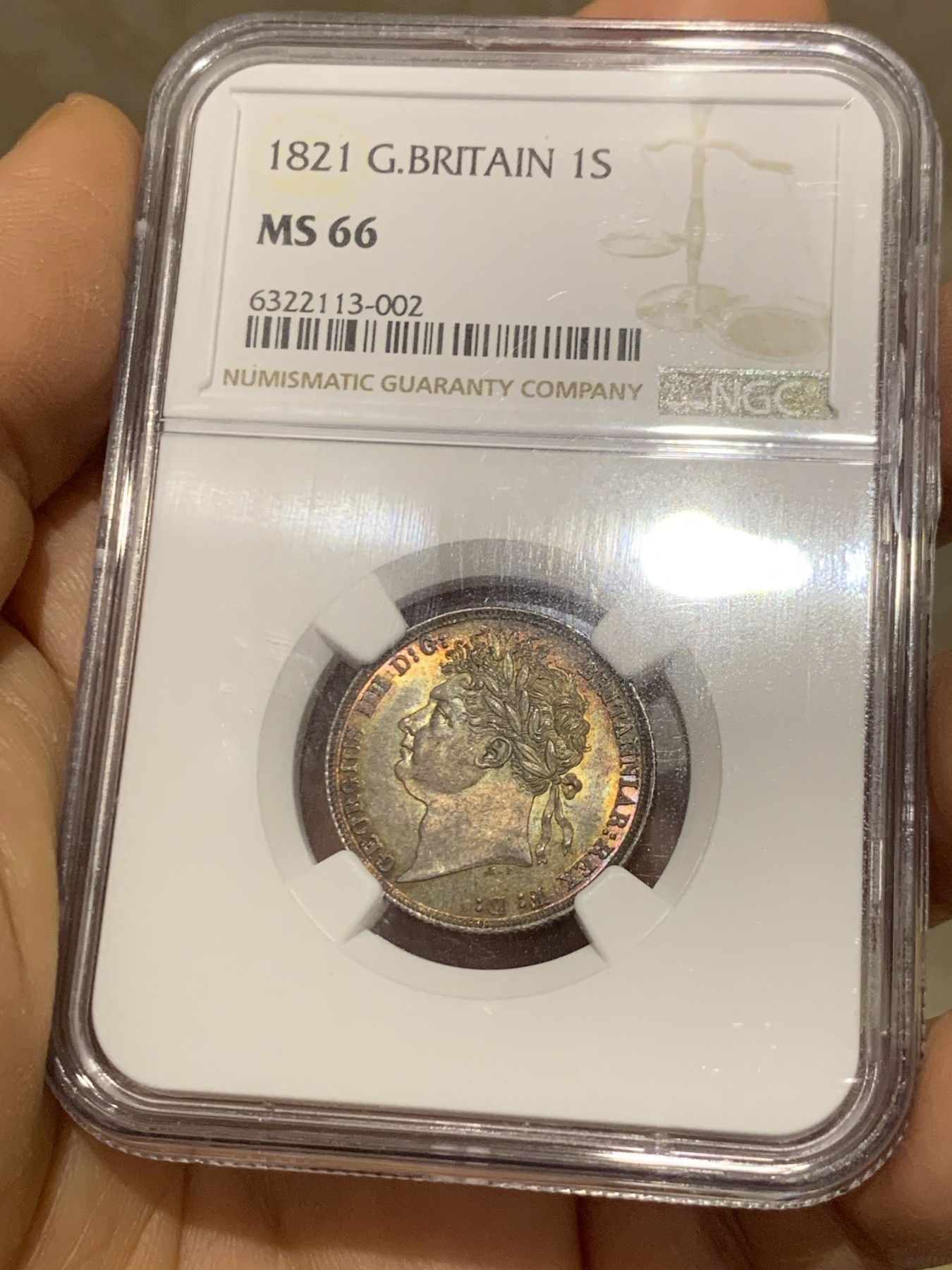 《竞宝斋》圣诞专辑  第二场  第228场 定制纪念章相赠 (全场顺丰包邮) NGC-MS66 英国1821年乔治四世1先令银币。币面环绕暖色系包浆，橘黄，红酒色，梅红，紫罗兰循序渐进。双面经典，正面头像来自皮斯特鲁奇；背面三花图案来自简·帕皮提斯特·梅林，签名隐藏在内齿。三叶草上暗记wwp为mint master的简拼。美国知名币商66+售价1850美金。