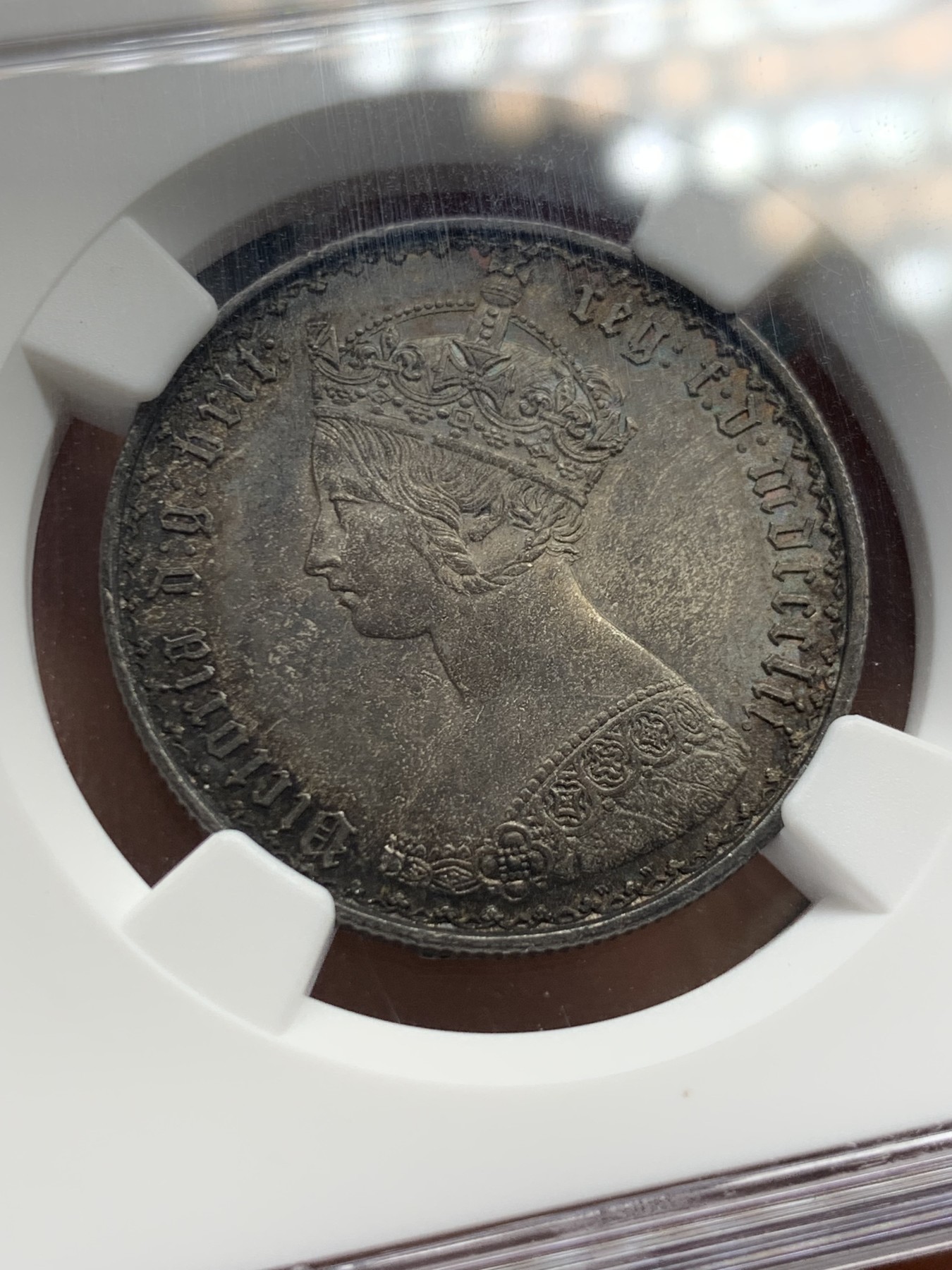 《竞宝斋》圣诞专辑  第二场  第228场 定制纪念章相赠 (全场顺丰包邮) NGC-MS63 英国1852年维多利亚女王哥特福林银币。正面包浆沉稳古气，但又能透出隐约的酒红光芒，背面是极其漂亮的五彩彩虹色过渡自然。这枚是整个系列的第一年，第一版女王面部线条和蔼柔美，值得入手。