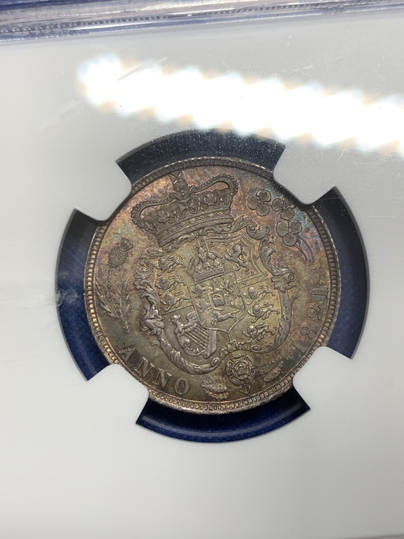 《竞宝斋》圣诞专辑  第二场  第228场 定制纪念章相赠 (全场顺丰包邮) NGC-MS66 英国1821年乔治四世1先令银币。币面环绕暖色系包浆，橘黄，红酒色，梅红，紫罗兰循序渐进。双面经典，正面头像来自皮斯特鲁奇；背面三花图案来自简·帕皮提斯特·梅林，签名隐藏在内齿。三叶草上暗记wwp为mint master的简拼。美国知名币商66+售价1850美金。