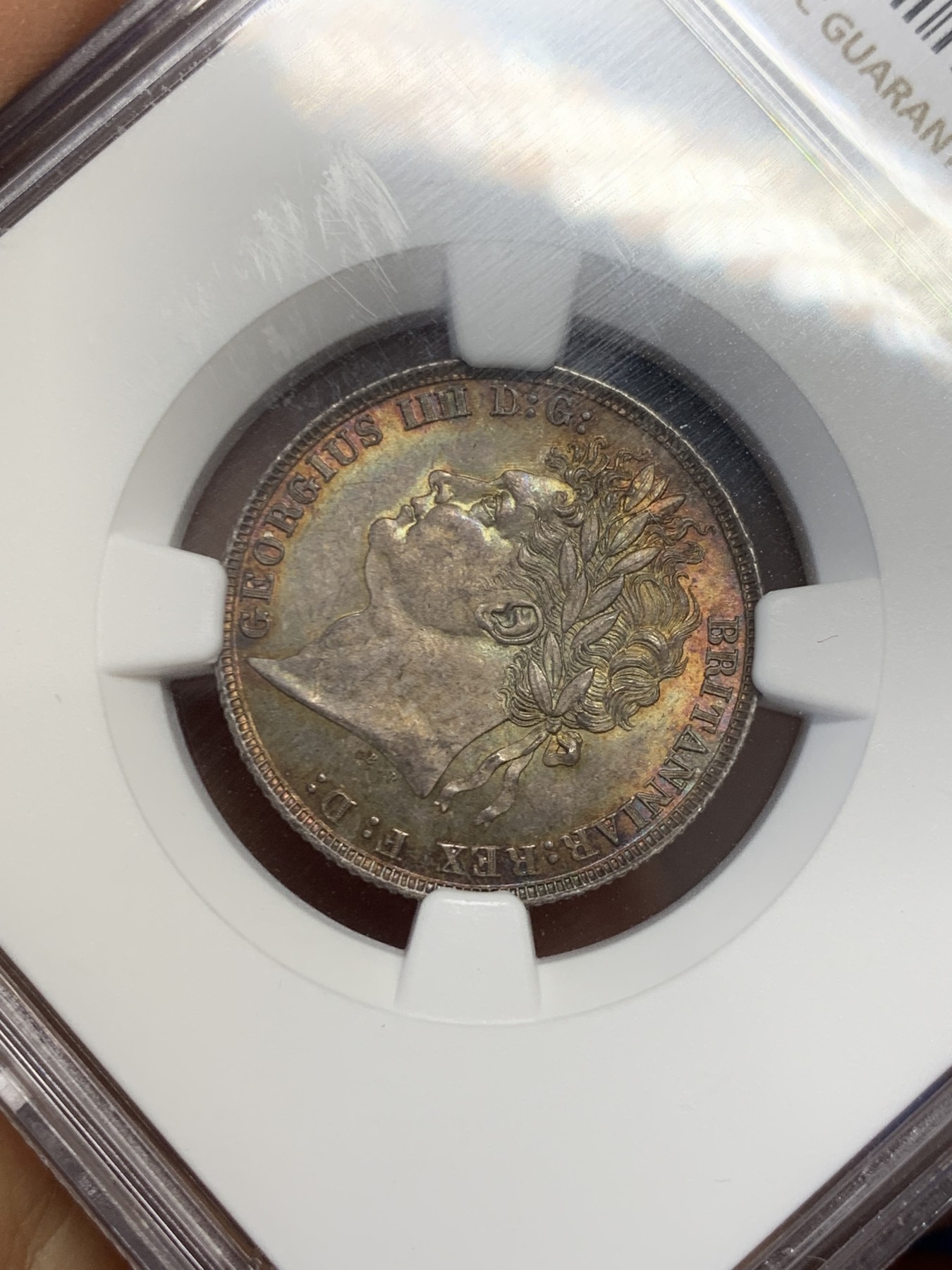 《竞宝斋》圣诞专辑  第二场  第228场 定制纪念章相赠 (全场顺丰包邮) NGC-MS66 英国1821年乔治四世1先令银币。币面环绕暖色系包浆，橘黄，红酒色，梅红，紫罗兰循序渐进。双面经典，正面头像来自皮斯特鲁奇；背面三花图案来自简·帕皮提斯特·梅林，签名隐藏在内齿。三叶草上暗记wwp为mint master的简拼。美国知名币商66+售价1850美金。