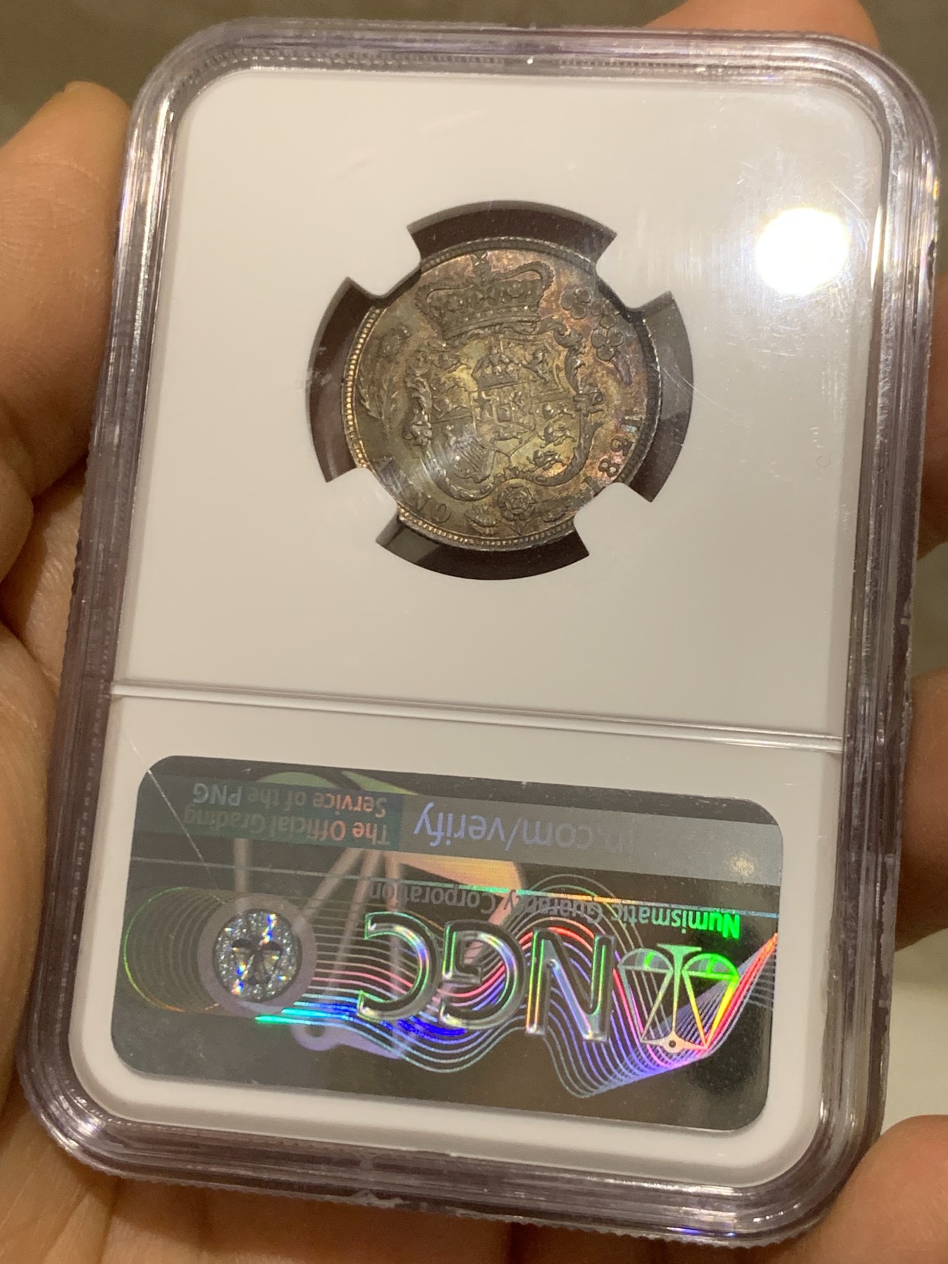 《竞宝斋》圣诞专辑  第二场  第228场 定制纪念章相赠 (全场顺丰包邮) NGC-MS66 英国1821年乔治四世1先令银币。币面环绕暖色系包浆，橘黄，红酒色，梅红，紫罗兰循序渐进。双面经典，正面头像来自皮斯特鲁奇；背面三花图案来自简·帕皮提斯特·梅林，签名隐藏在内齿。三叶草上暗记wwp为mint master的简拼。美国知名币商66+售价1850美金。