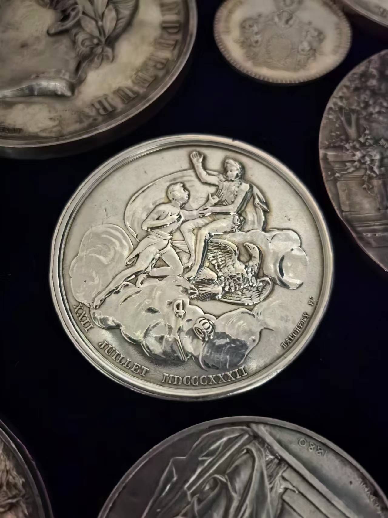 1832年拿破仑银章，父子相会，直径51mm。赖希施塔特公爵拿破仑·弗朗茨·波拿巴在维也纳施恩布伦宫逝世，正面是他父亲拿破仑一世的死亡面具，背面拿破仑一世和鹰坐在云端，伸出手迎接他的儿子。 此章银版甚少，丰饶角argent边铭，表面有清洁痕迹。虽然不是原铸，也有120年以上的历史了。此章为Bramsen《拿破仑大帝的章牌目录》第三册封面章。