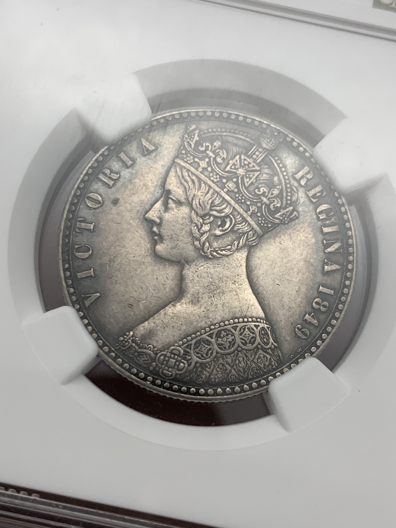 《竞宝斋》第240场-周日，周一 年终尾场 (全场包邮) NGC-AU55 英国1849年维多利亚无神弗洛林银币 英国第一枚弗洛林 第一枚没有D.G(君权神授) 正面是威廉怀恩作品 背面有代表英格兰、苏格兰、威尔士的三花 名誉品种 打制精美 五官皇冠服饰都清晰可见 特有的英系黑彩 钱币背后的故事丰富 只发行一年稀有（N家评级标签印成1949，难得的错误成了唯一）