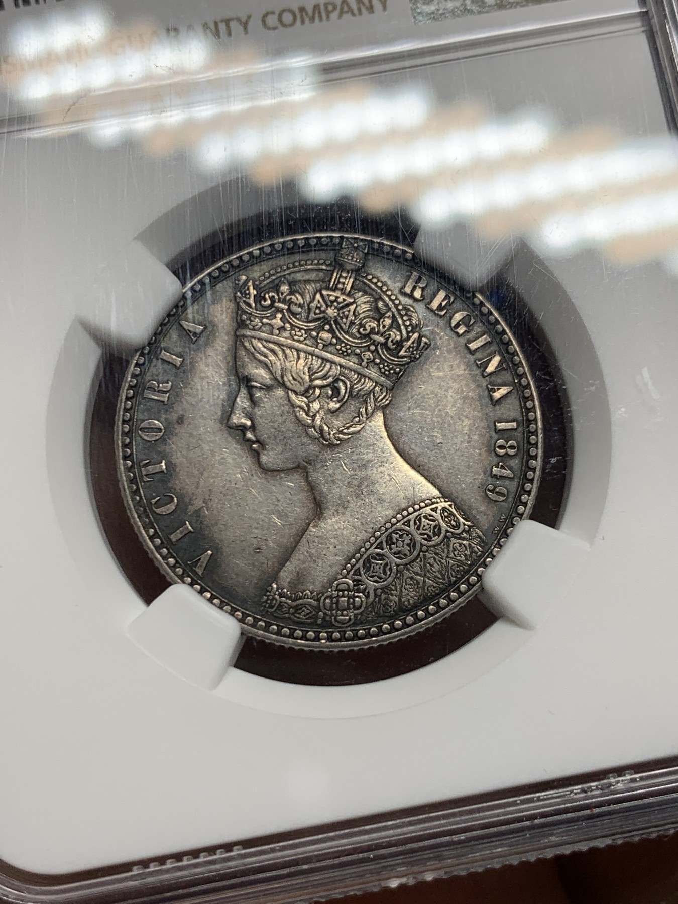 《竞宝斋》第240场-周日，周一 年终尾场 (全场包邮) NGC-AU55 英国1849年维多利亚无神弗洛林银币 英国第一枚弗洛林 第一枚没有D.G(君权神授) 正面是威廉怀恩作品 背面有代表英格兰、苏格兰、威尔士的三花 名誉品种 打制精美 五官皇冠服饰都清晰可见 特有的英系黑彩 钱币背后的故事丰富 只发行一年稀有（N家评级标签印成1949，难得的错误成了唯一）