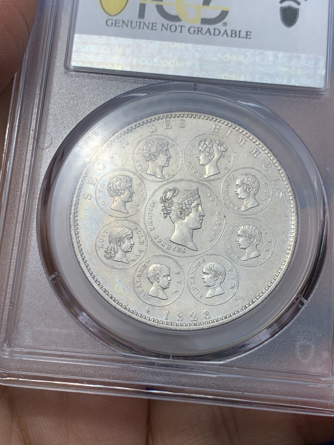 《竞宝斋》第242场-周日，周一 新年开场 (全场包邮) PCGS UNC 德国 巴伐利亚1828年祝福王室历史协定泰勒银币，直径38mm，重28.06g，纯度83.3%。背面中央为王后特蕾莎头像，其左侧为四位王子头像，右侧为四位公主头像。细节清晰状态很不错。