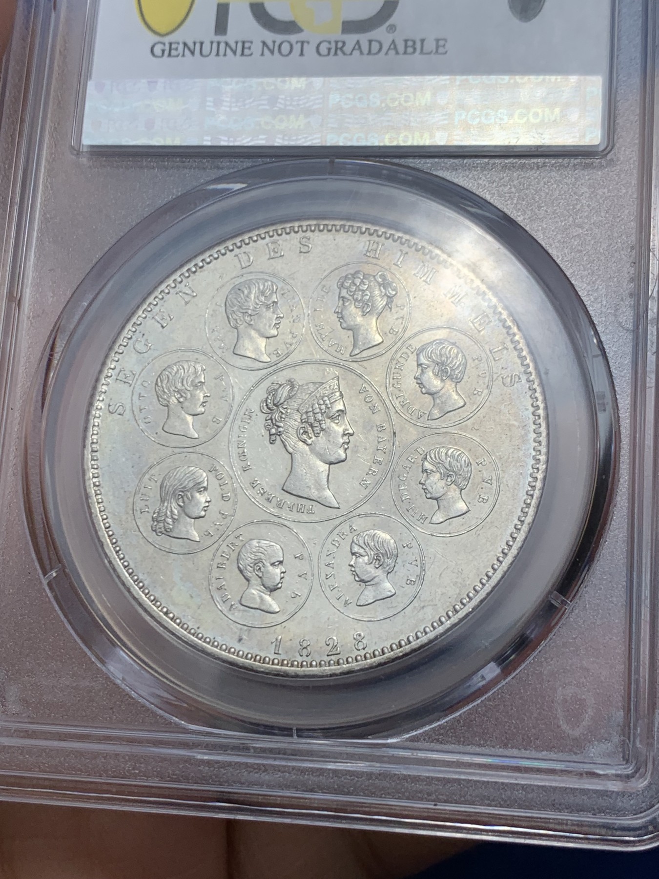 《竞宝斋》第242场-周日，周一 新年开场 (全场包邮) PCGS UNC 德国 巴伐利亚1828年祝福王室历史协定泰勒银币，直径38mm，重28.06g，纯度83.3%。背面中央为王后特蕾莎头像，其左侧为四位王子头像，右侧为四位公主头像。细节清晰状态很不错。