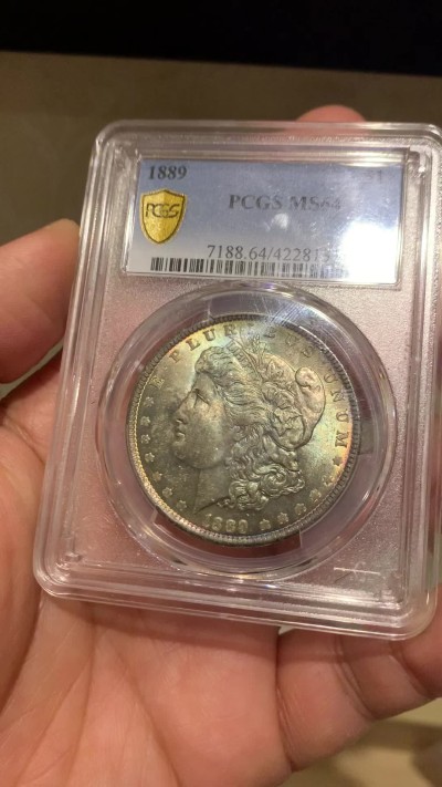 《竞宝斋》第243场-周日，周一 新年开场 (全场包邮) PCGS MS64 美国1889年摩根银币P版，极美原汁原味五彩包浆，包浆醇厚浓郁，打制精美，状态一流。币面五彩斑斓，炫耀夺目，状态和品质不输现在的65分，市场上稀少年份版本的摩根币。