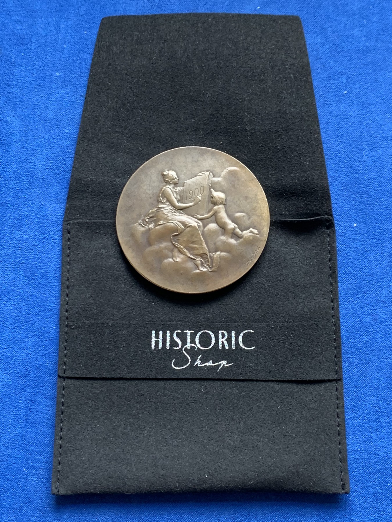 《竞宝斋》第261场-周日，周一，周二 3场连拍 (全场包邮) 法国章牌艺术大师丹尼尔·杜普伊Daniel Dupuis作品 巴黎造币厂1900年参展国际博览会设计雕刻的纪念章 直径50mm 重59.2克 丰饶角铜标 正面：主题为“历史记录（l'Histoire）”的场景 优雅女神手捧书卷 裙子随风轻盈摇曳 背面图案是压铸机 巴黎造币厂