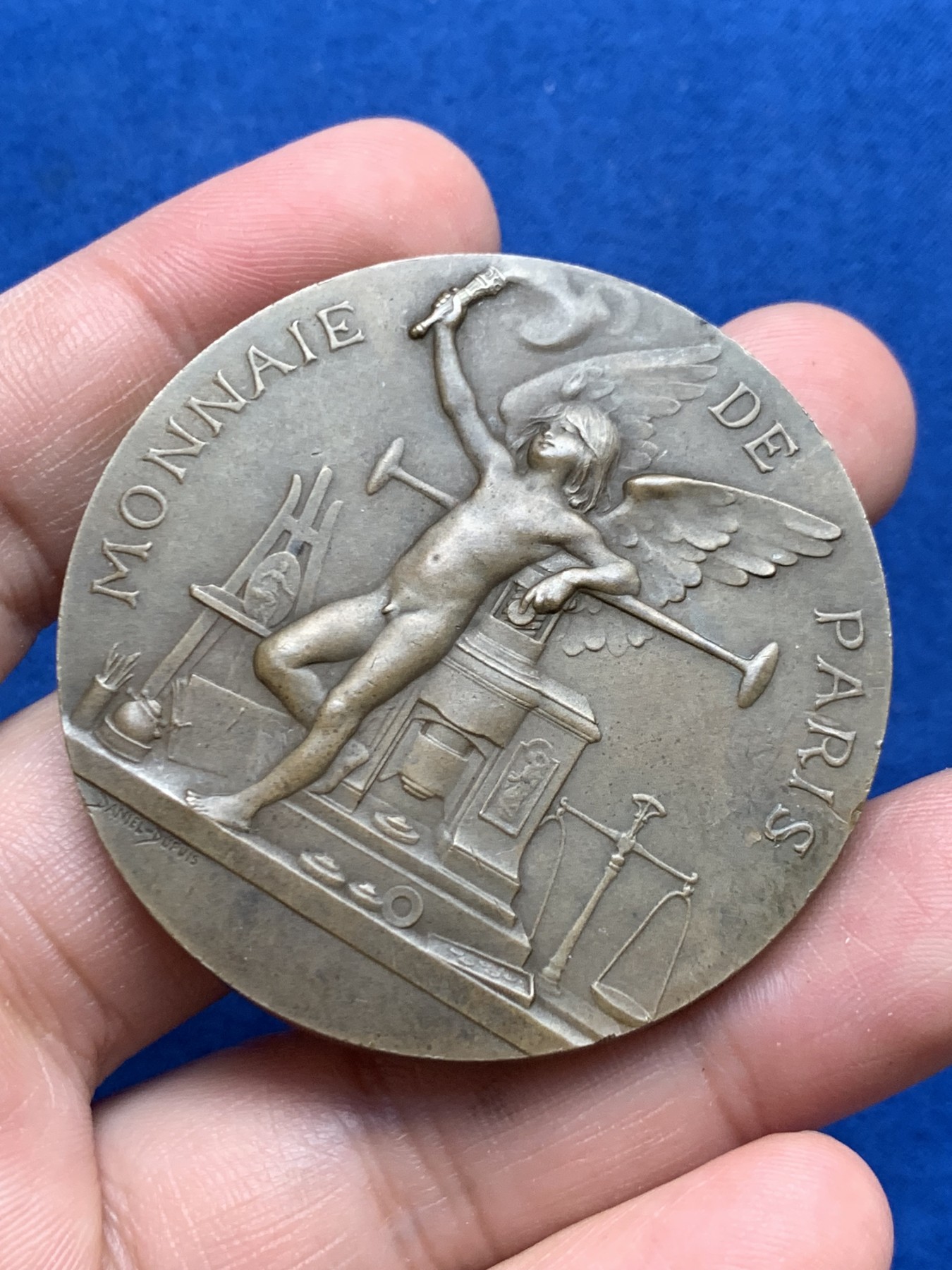 《竞宝斋》第261场-周日，周一，周二 3场连拍 (全场包邮) 法国章牌艺术大师丹尼尔·杜普伊Daniel Dupuis作品 巴黎造币厂1900年参展国际博览会设计雕刻的纪念章 直径50mm 重59.2克 丰饶角铜标 正面：主题为“历史记录（l'Histoire）”的场景 优雅女神手捧书卷 裙子随风轻盈摇曳 背面图案是压铸机 巴黎造币厂