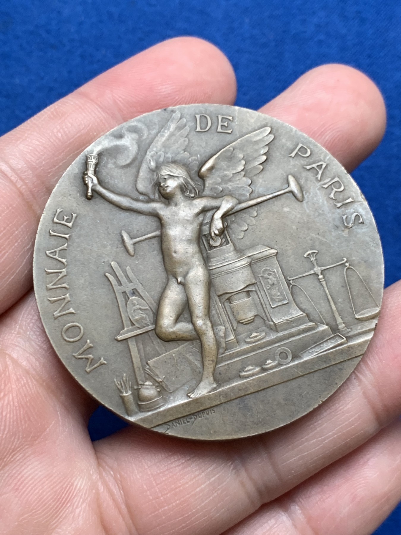 《竞宝斋》第261场-周日，周一，周二 3场连拍 (全场包邮) 法国章牌艺术大师丹尼尔·杜普伊Daniel Dupuis作品 巴黎造币厂1900年参展国际博览会设计雕刻的纪念章 直径50mm 重59.2克 丰饶角铜标 正面：主题为“历史记录（l'Histoire）”的场景 优雅女神手捧书卷 裙子随风轻盈摇曳 背面图案是压铸机 巴黎造币厂