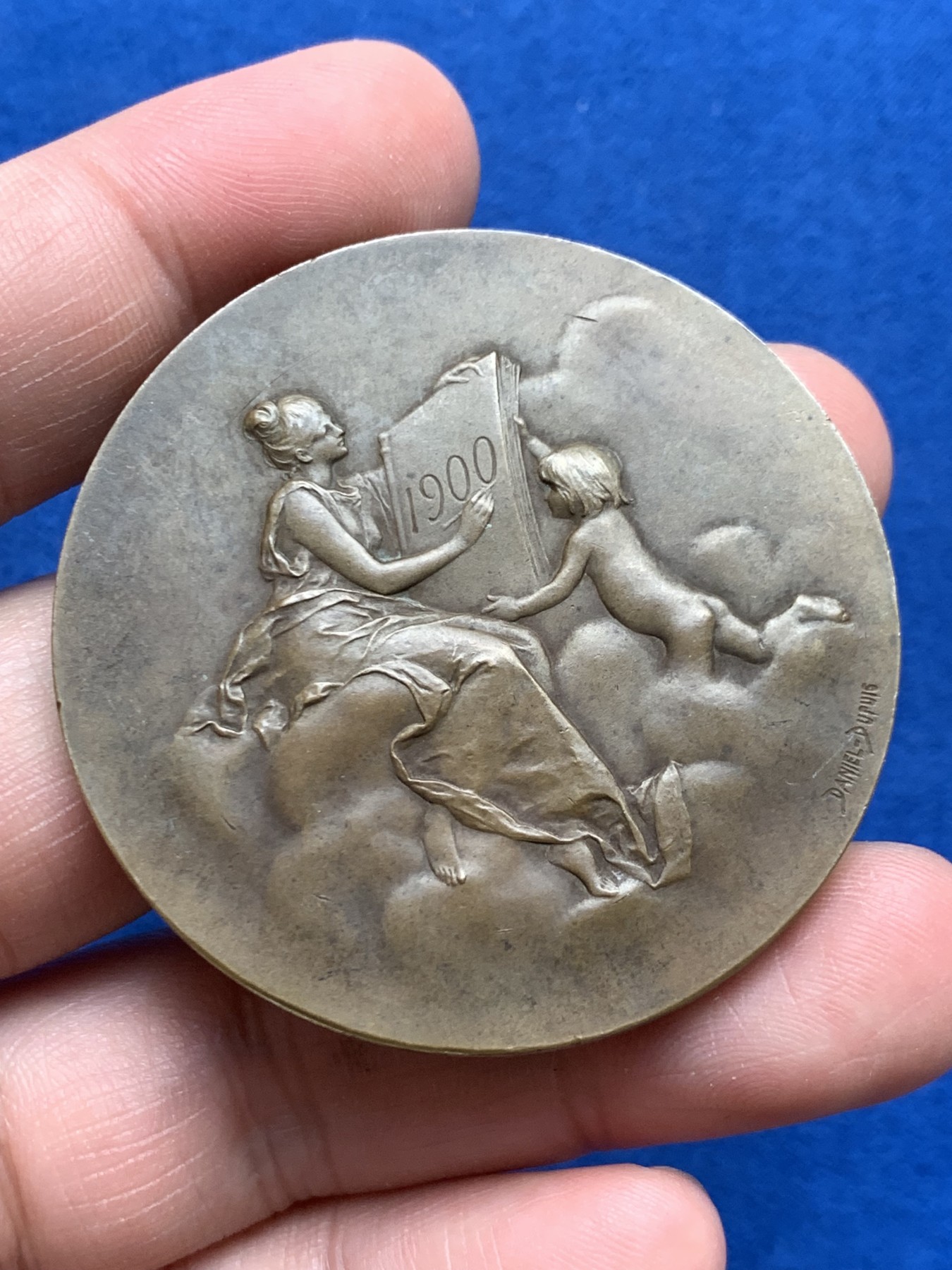 《竞宝斋》第261场-周日，周一，周二 3场连拍 (全场包邮) 法国章牌艺术大师丹尼尔·杜普伊Daniel Dupuis作品 巴黎造币厂1900年参展国际博览会设计雕刻的纪念章 直径50mm 重59.2克 丰饶角铜标 正面：主题为“历史记录（l'Histoire）”的场景 优雅女神手捧书卷 裙子随风轻盈摇曳 背面图案是压铸机 巴黎造币厂