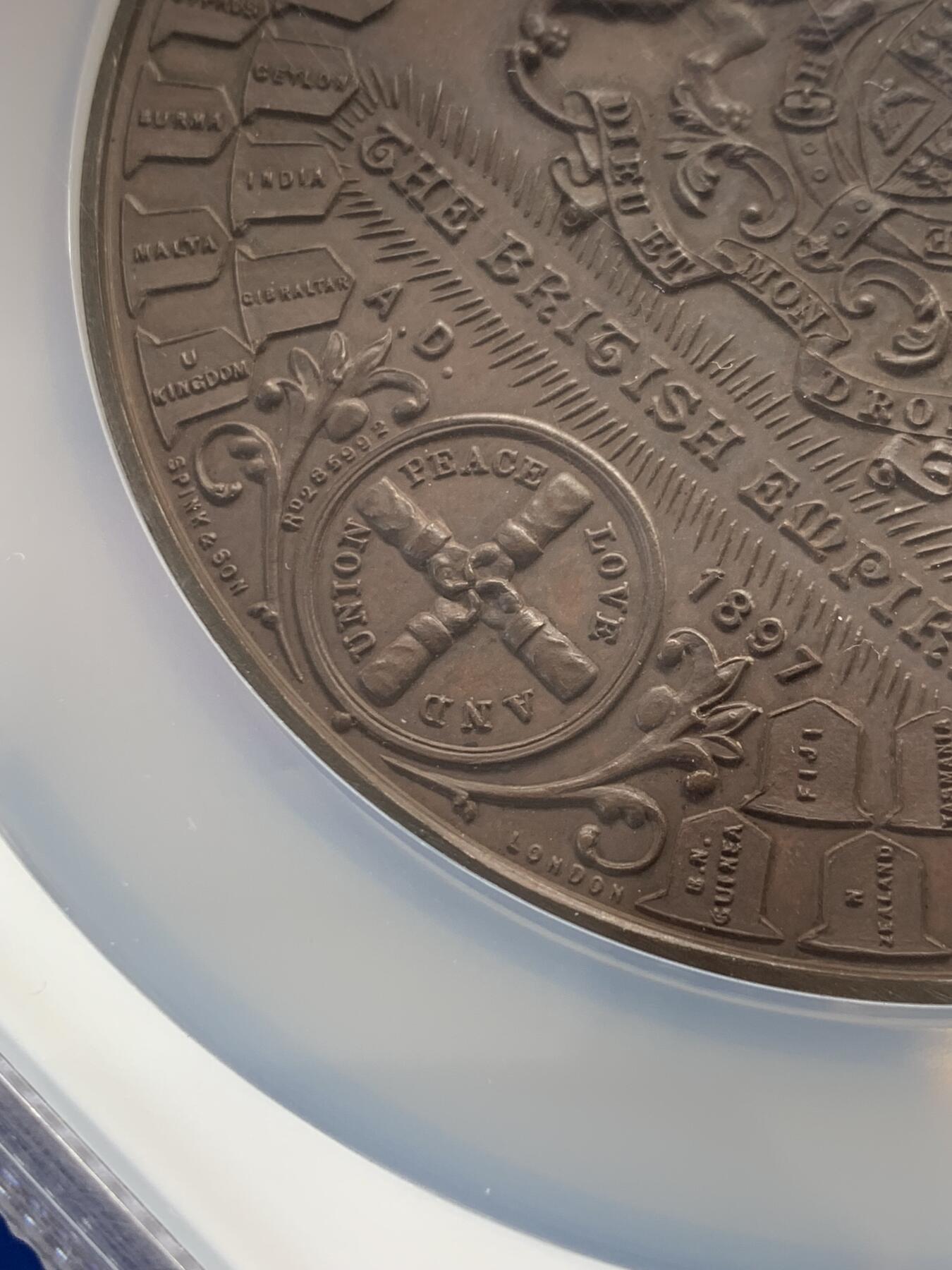 《竞宝斋》立夏专场特拍 （第2-1场）全场顺丰包邮 265场 NGC MS61BN 英国1897维多利亚钻石周年纪念铜章 大盒加厚 76MM 背后是双手合呈十字形，写着爱 和平 和 联合 55个盾牌上是英国领土以及殖民地名称 彰显日不落帝国的辉煌 也是英国帝国全球扩张的历史见证