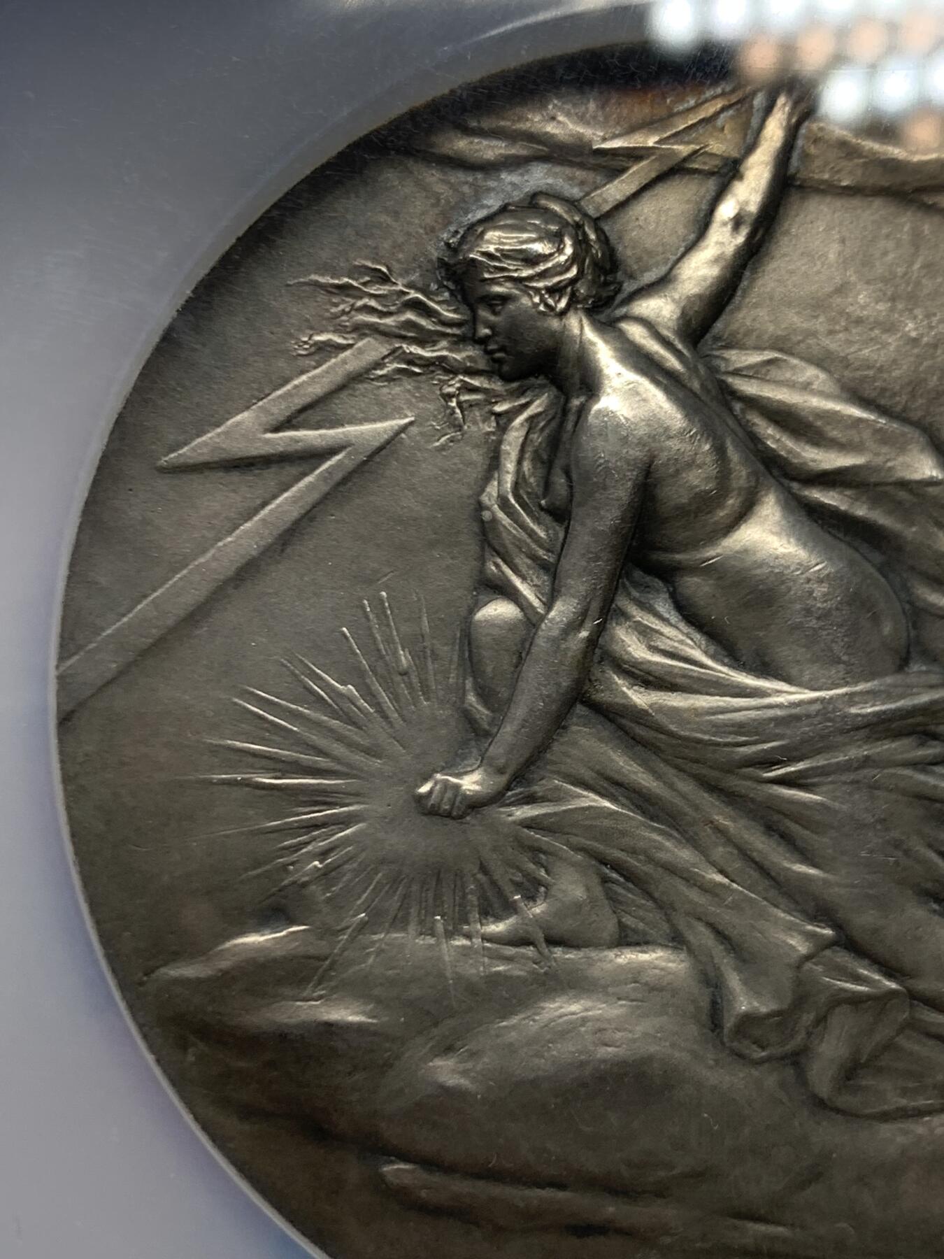 《竞宝斋》立夏专场特拍 （第2-1场）全场顺丰包邮 265场 NGC MS63 法国电力女神大银章，和法兰西银行百年、突尼斯开港都是68mm的精品大章，作者皮列是骑马鹰洋的雕刻师，法章名家。正面的裸身女神丰腴立体，背面是景观，一章两面都是精品。这个品种63高分罕见，章牌爱好者必冲。