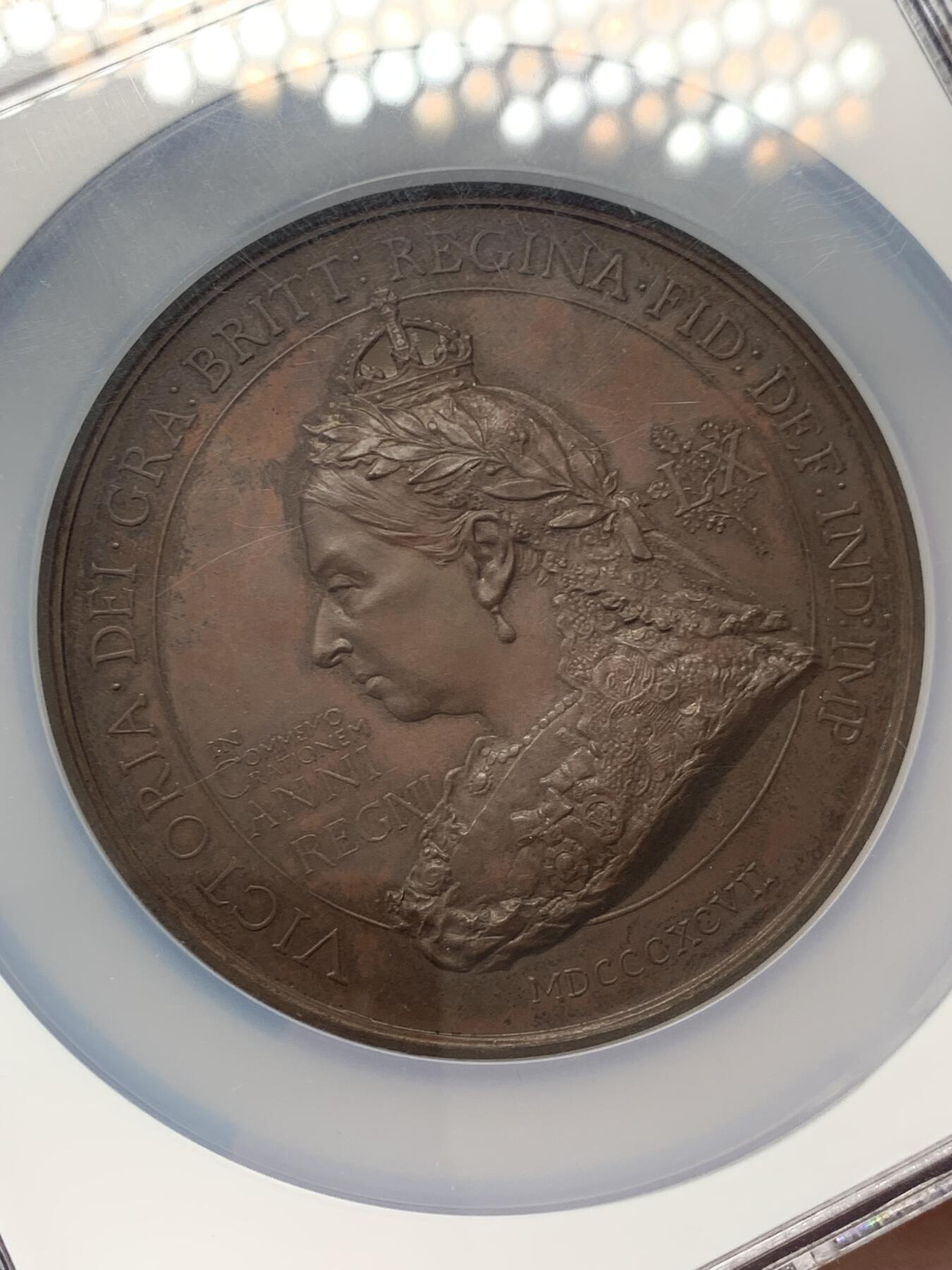 《竞宝斋》立夏专场特拍 （第2-1场）全场顺丰包邮 265场 NGC MS61BN 英国1897维多利亚钻石周年纪念铜章 大盒加厚 76MM 背后是双手合呈十字形，写着爱 和平 和 联合 55个盾牌上是英国领土以及殖民地名称 彰显日不落帝国的辉煌 也是英国帝国全球扩张的历史见证