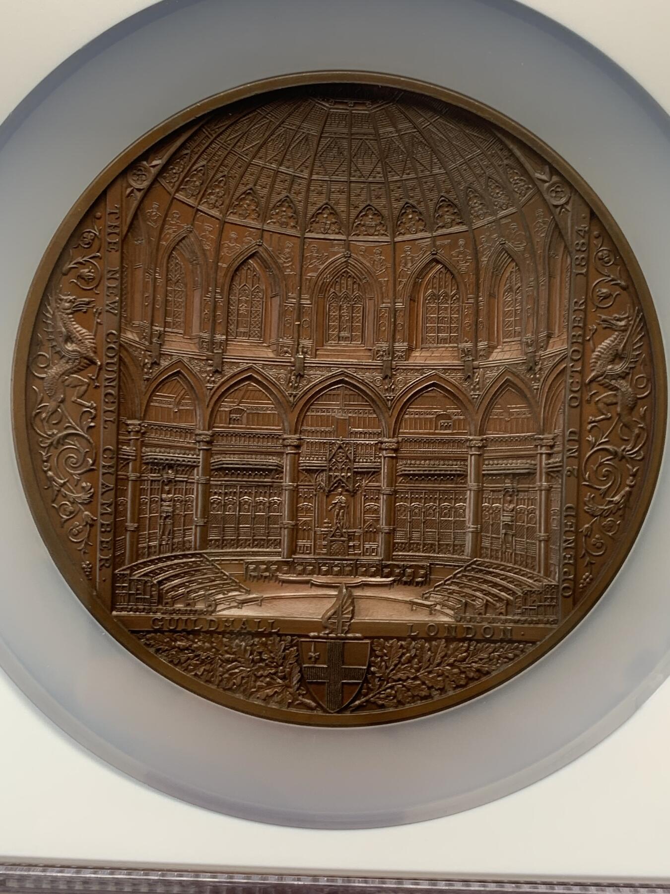 《竞宝斋》立夏专场特拍 （第2-1场）全场顺丰包邮 265场 NGC MS64BN 1884年英国伦敦金融城系列 建筑三杰之一 大不列颠市政厅铜牌新议会厅开幕 伦敦造币厂 作者JS & AB Wyon 直径77毫米 正面是伦迪尼亚 商业和治安法官出席 向她的议会发表讲话 背面是市政厅内景 此章是任何大教堂和建筑相关奖牌的高级收藏者的必备品