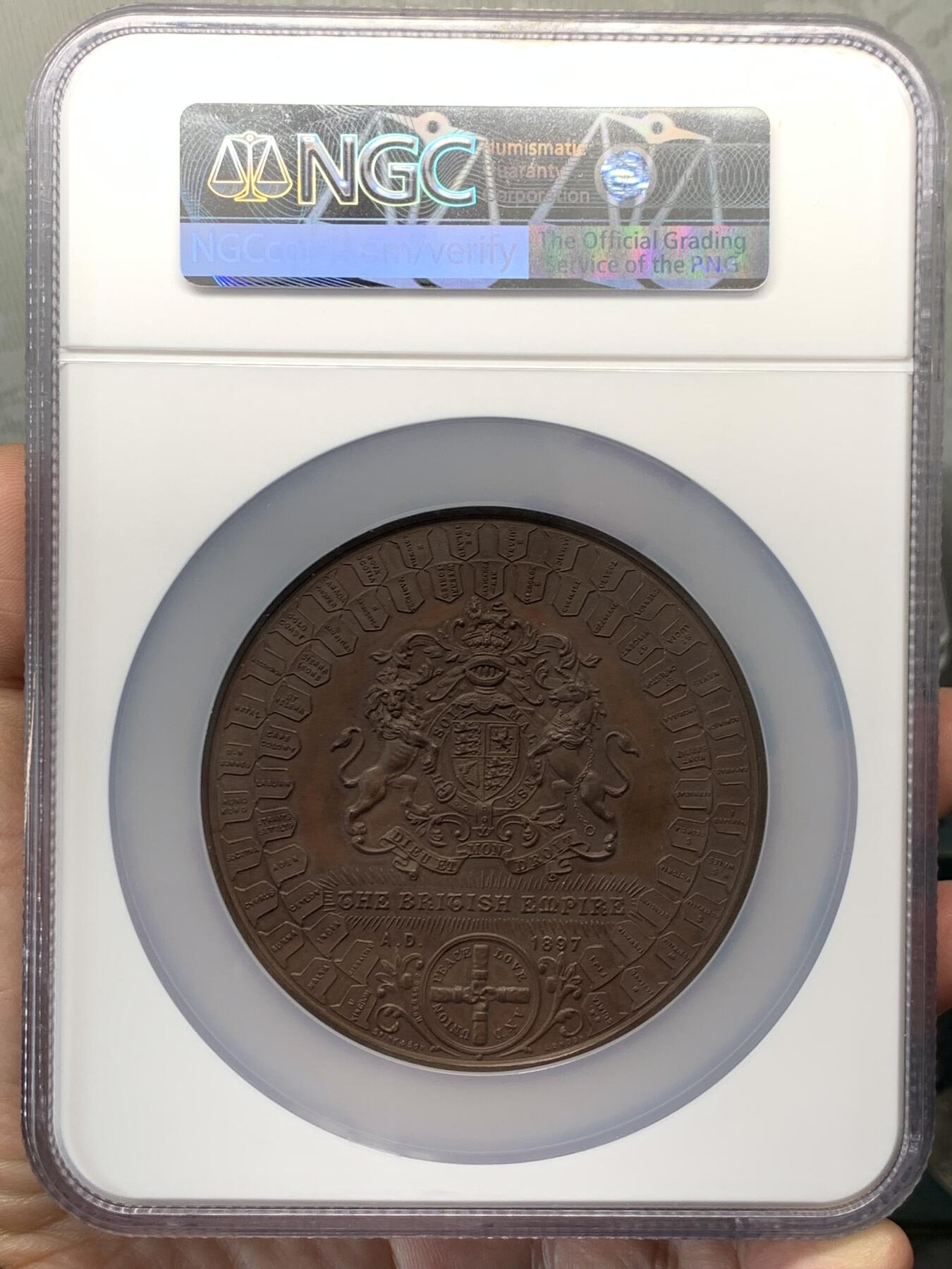 《竞宝斋》立夏专场特拍 （第2-1场）全场顺丰包邮 265场 NGC MS61BN 英国1897维多利亚钻石周年纪念铜章 大盒加厚 76MM 背后是双手合呈十字形，写着爱 和平 和 联合 55个盾牌上是英国领土以及殖民地名称 彰显日不落帝国的辉煌 也是英国帝国全球扩张的历史见证