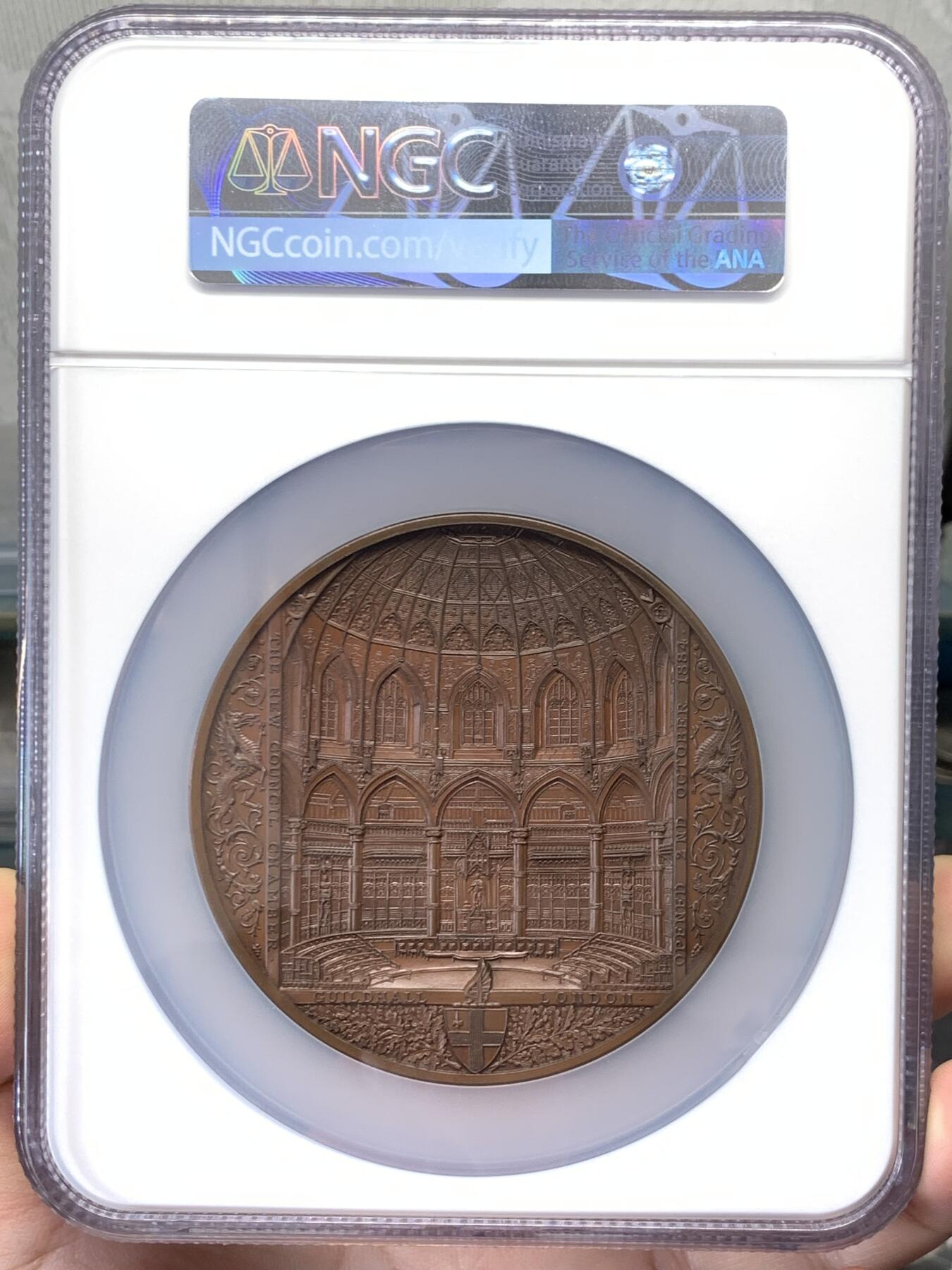 《竞宝斋》立夏专场特拍 （第2-1场）全场顺丰包邮 265场 NGC MS64BN 1884年英国伦敦金融城系列 建筑三杰之一 大不列颠市政厅铜牌新议会厅开幕 伦敦造币厂 作者JS & AB Wyon 直径77毫米 正面是伦迪尼亚 商业和治安法官出席 向她的议会发表讲话 背面是市政厅内景 此章是任何大教堂和建筑相关奖牌的高级收藏者的必备品