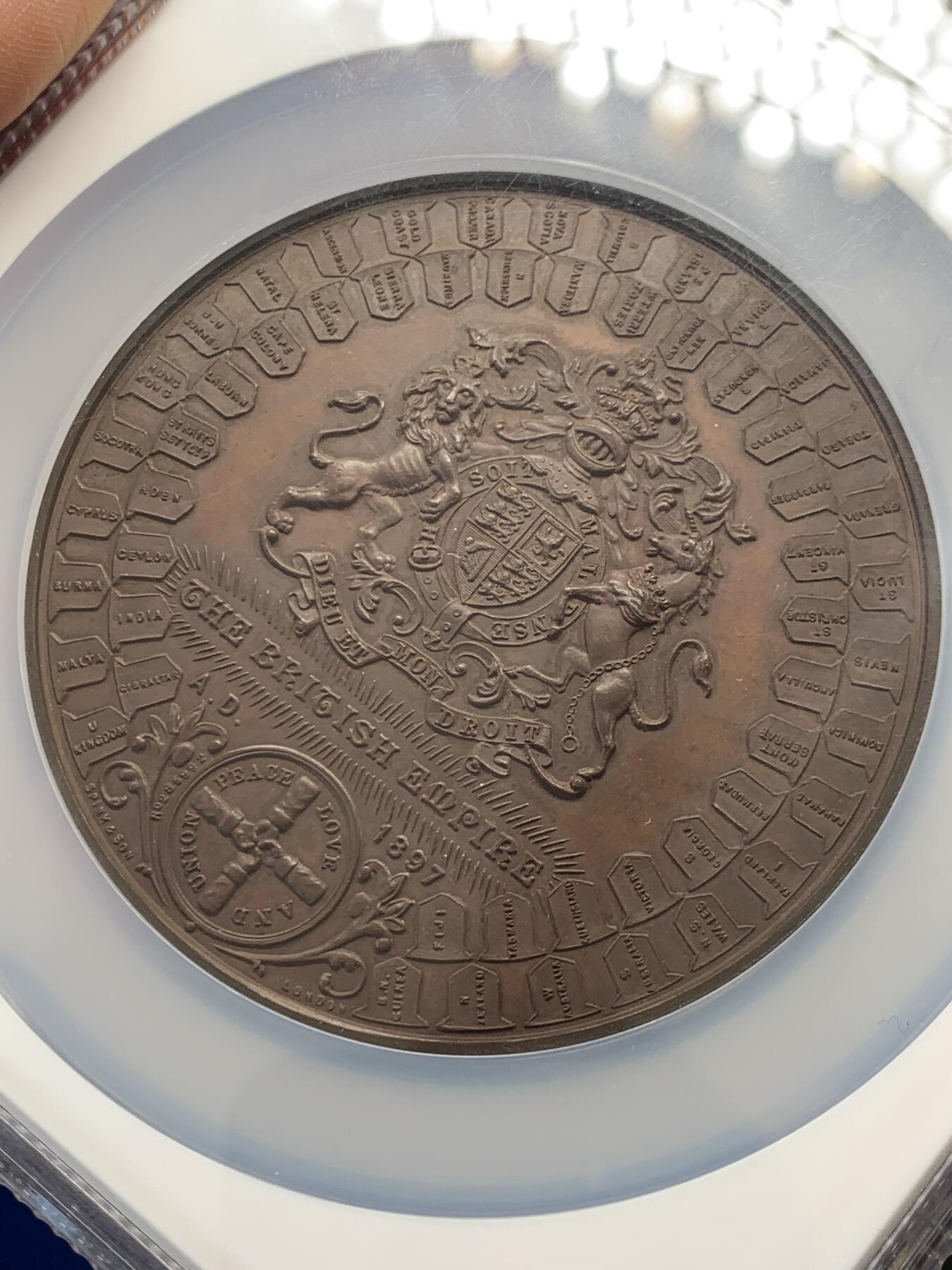 《竞宝斋》立夏专场特拍 （第2-1场）全场顺丰包邮 265场 NGC MS61BN 英国1897维多利亚钻石周年纪念铜章 大盒加厚 76MM 背后是双手合呈十字形，写着爱 和平 和 联合 55个盾牌上是英国领土以及殖民地名称 彰显日不落帝国的辉煌 也是英国帝国全球扩张的历史见证